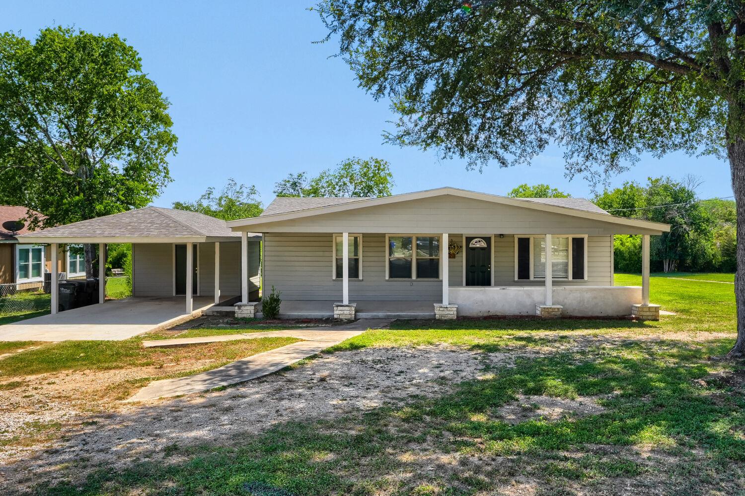 A welcoming front porch and detached carport anch