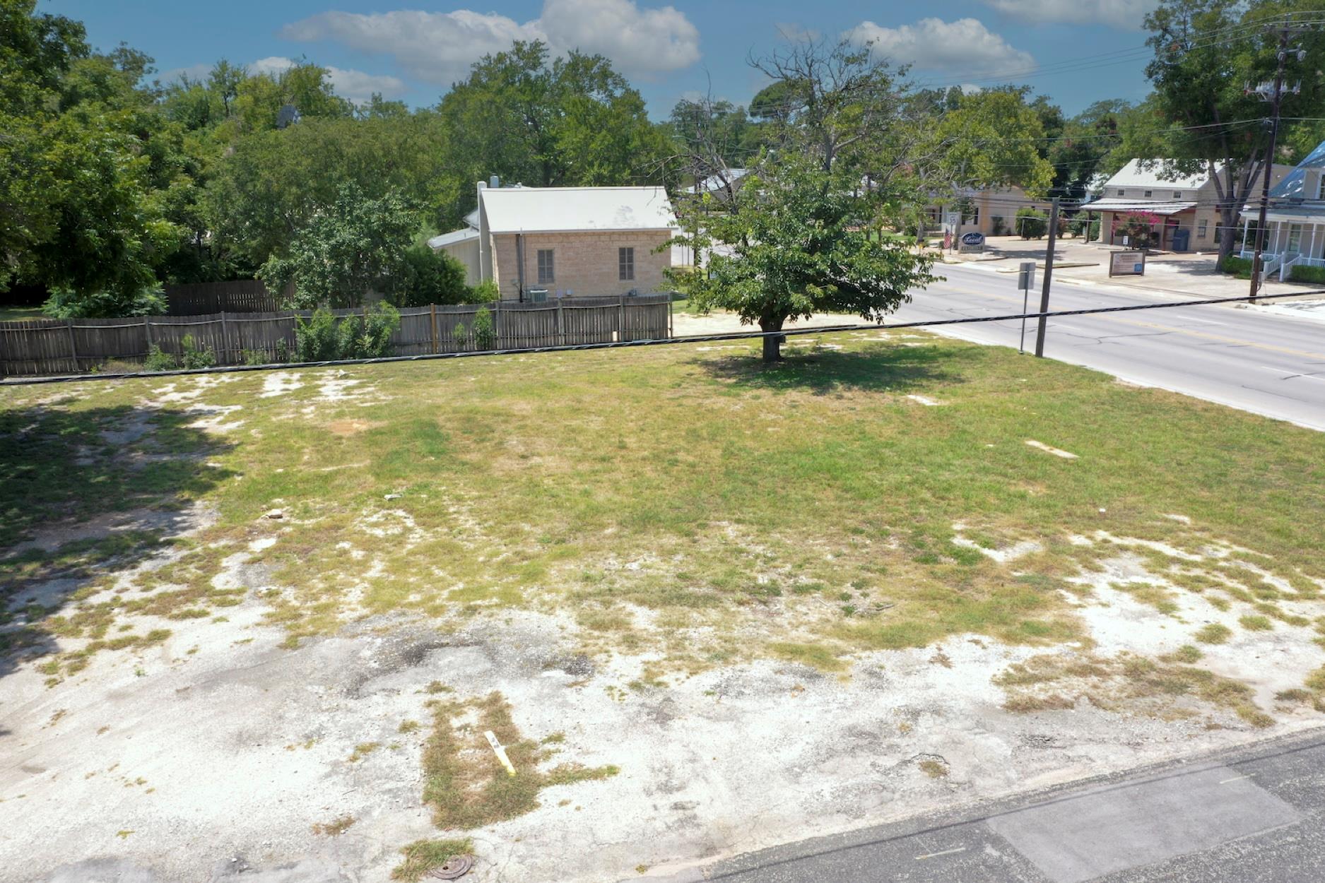 An open grassy lot bordered by mature trees stand