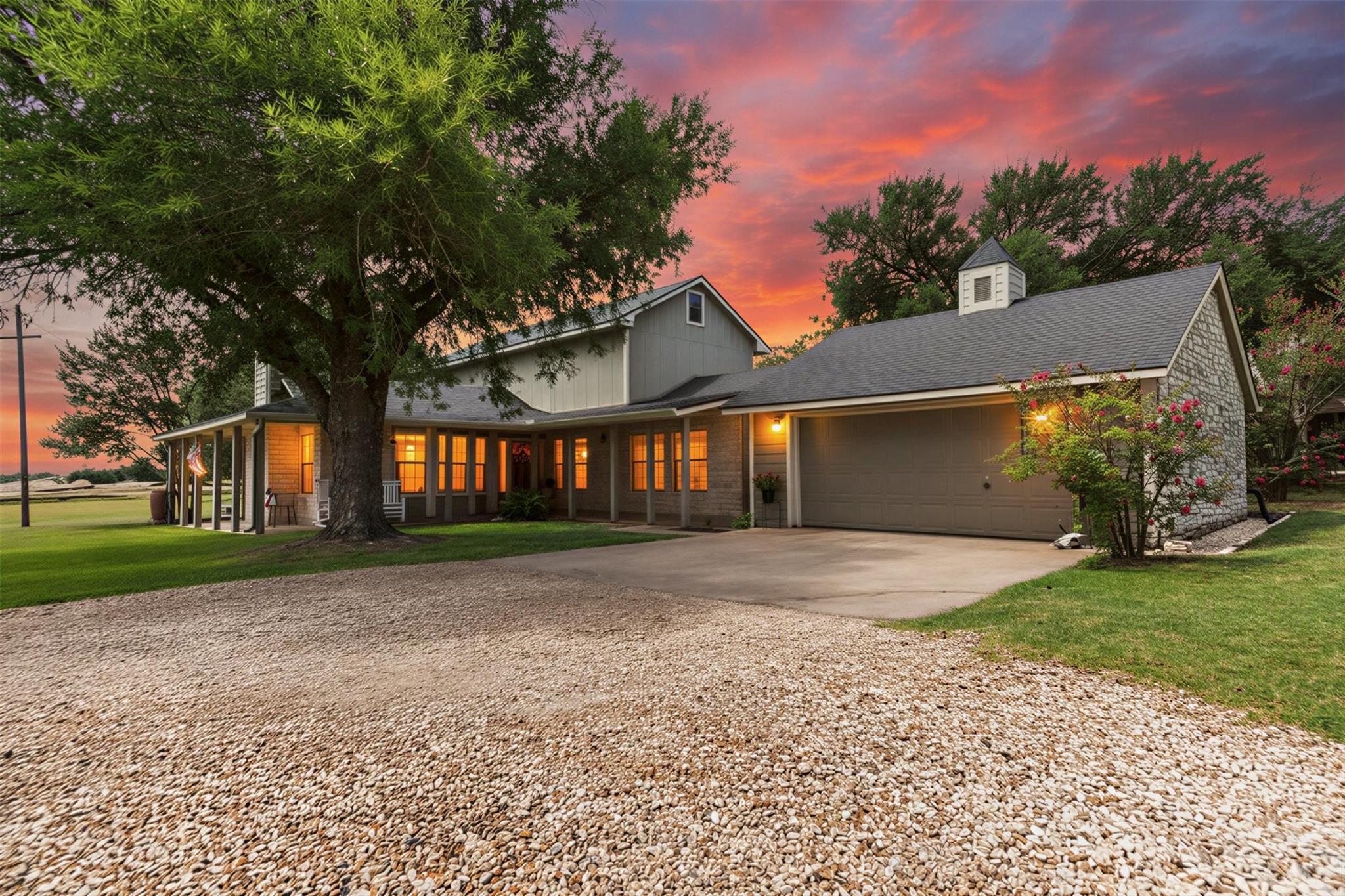 Mature trees frame a classic stone and siding ext