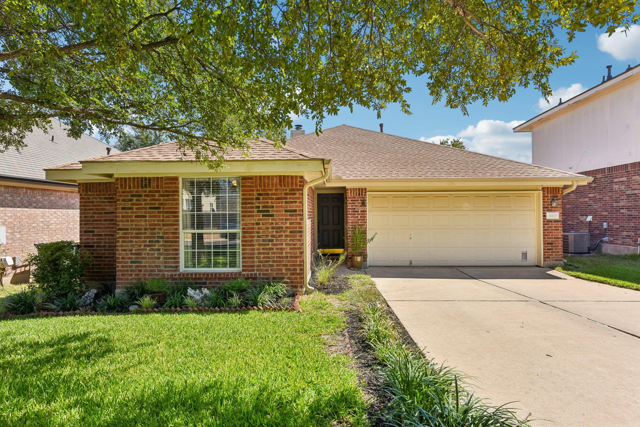 Mature trees shade a classic brick exterior featu