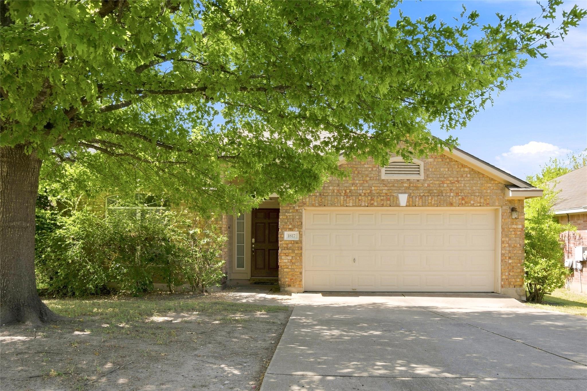 Mature shade trees frame a classic brick facade f