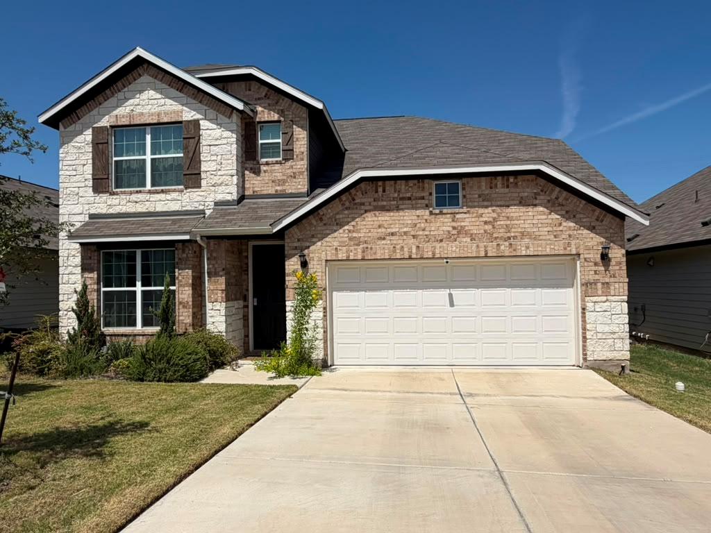 Two-story brick and stone facade elements complem