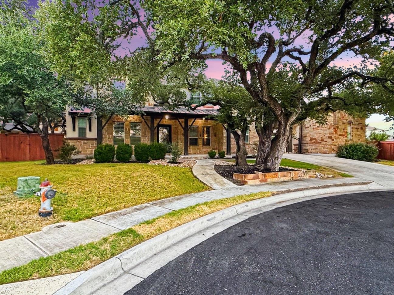 Mature shade trees frame a classic stone facade a