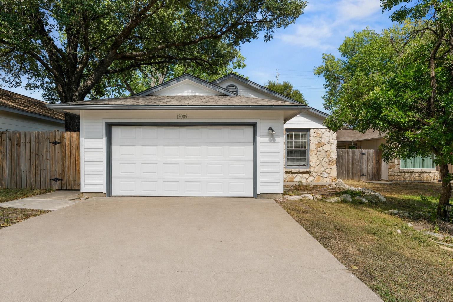 Established trees shade a concrete driveway leadi