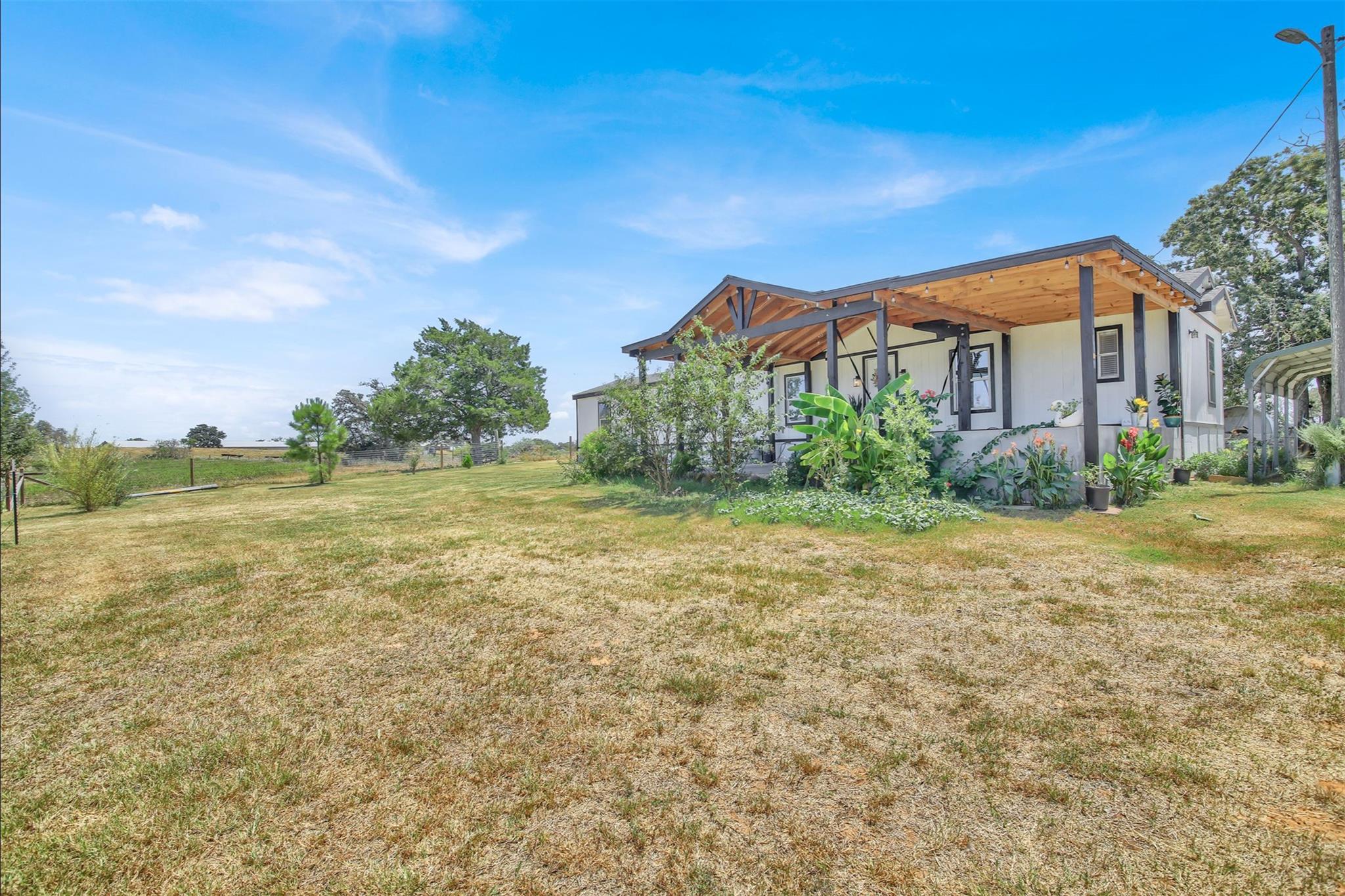 An expansive grassy yard surrounds the home featu
