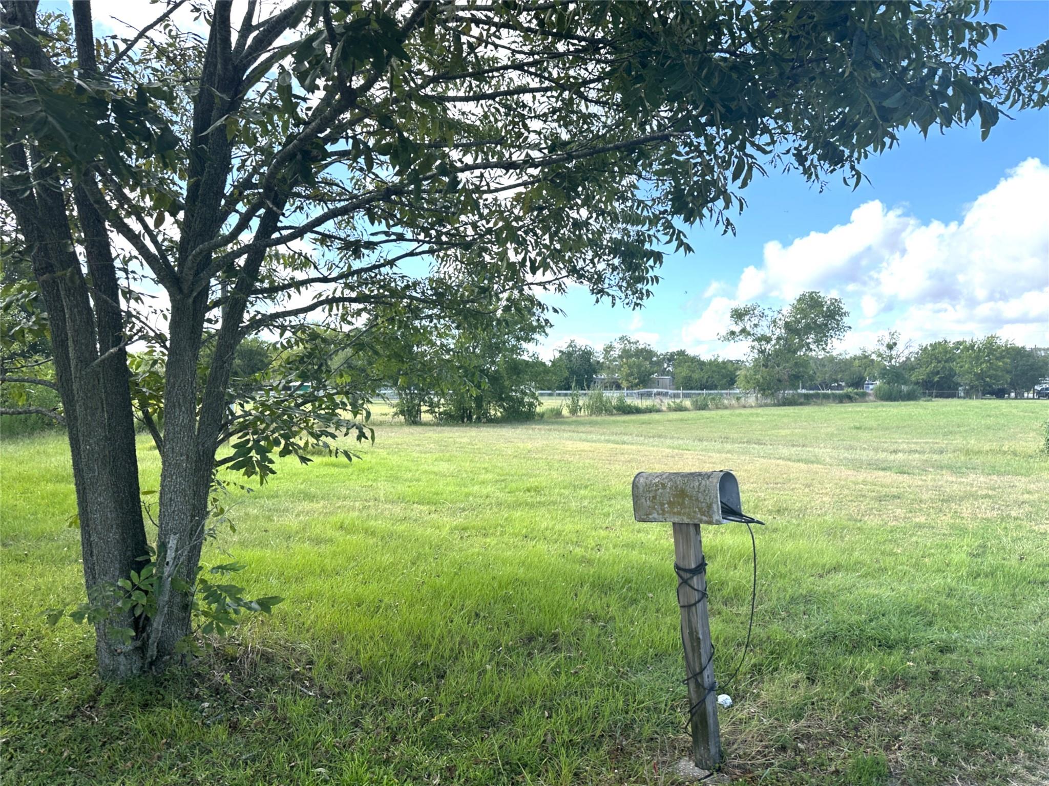 Mature trees frame a sprawling grassy lawn under 