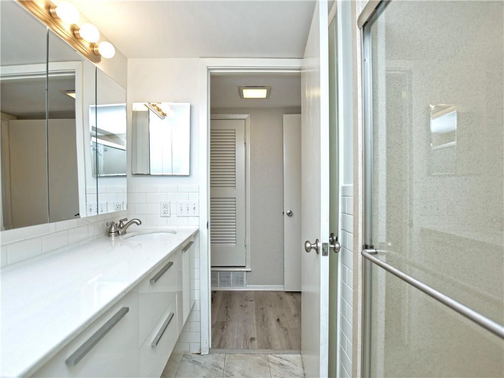 Full bath with vanity, a stall shower, light wood