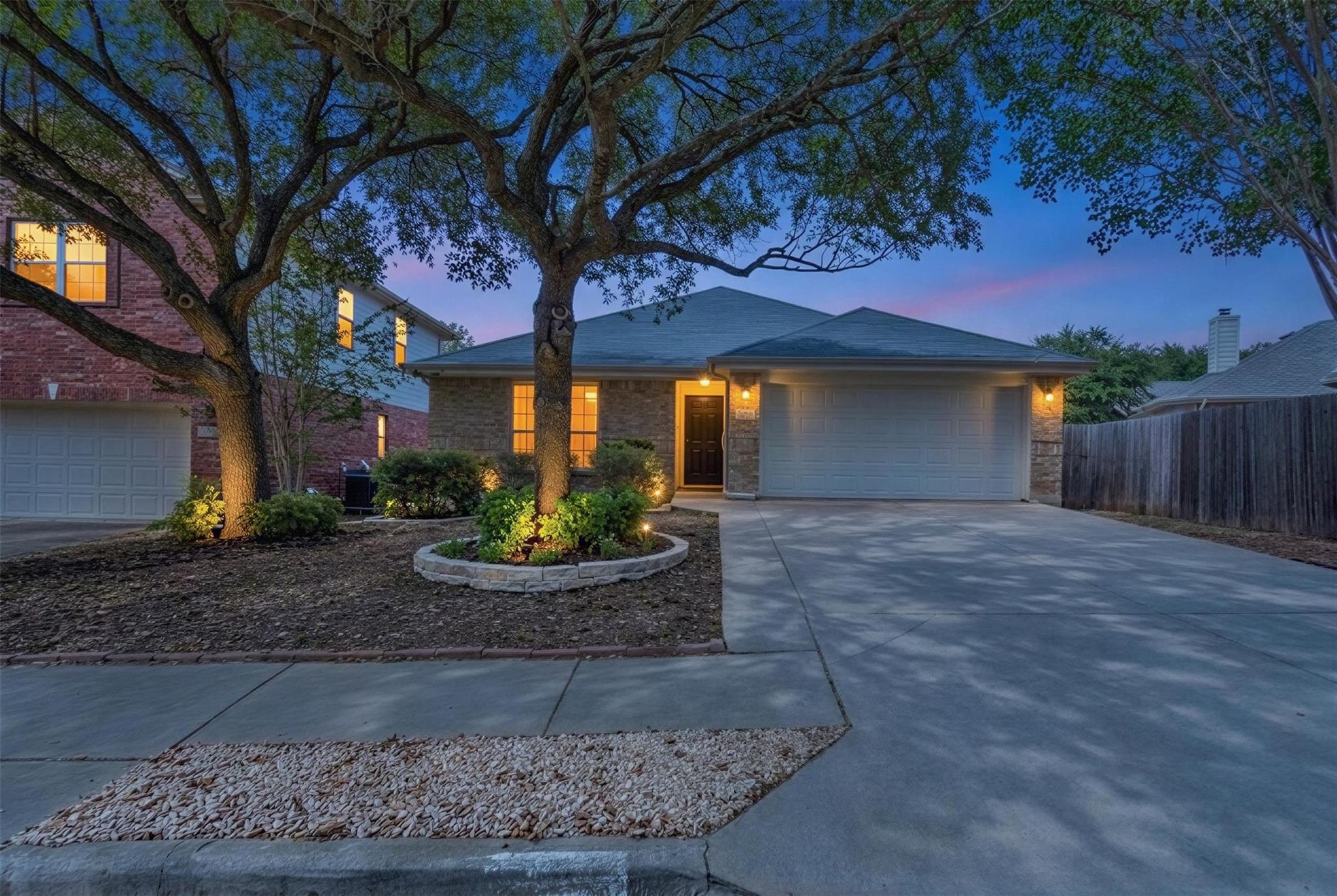 Mature trees shade the concrete driveway leading 