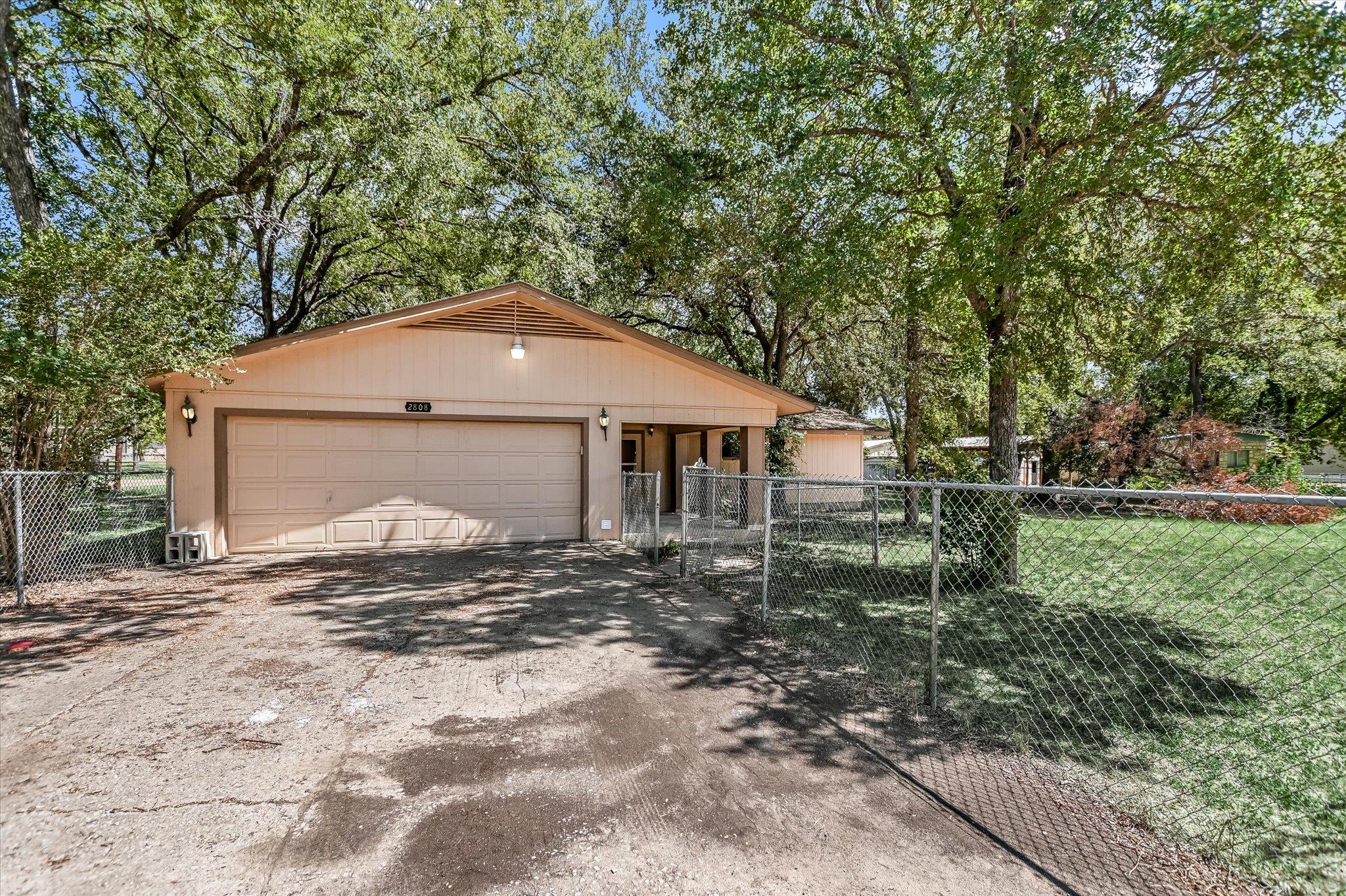 Mature trees shade a spacious driveway leading to