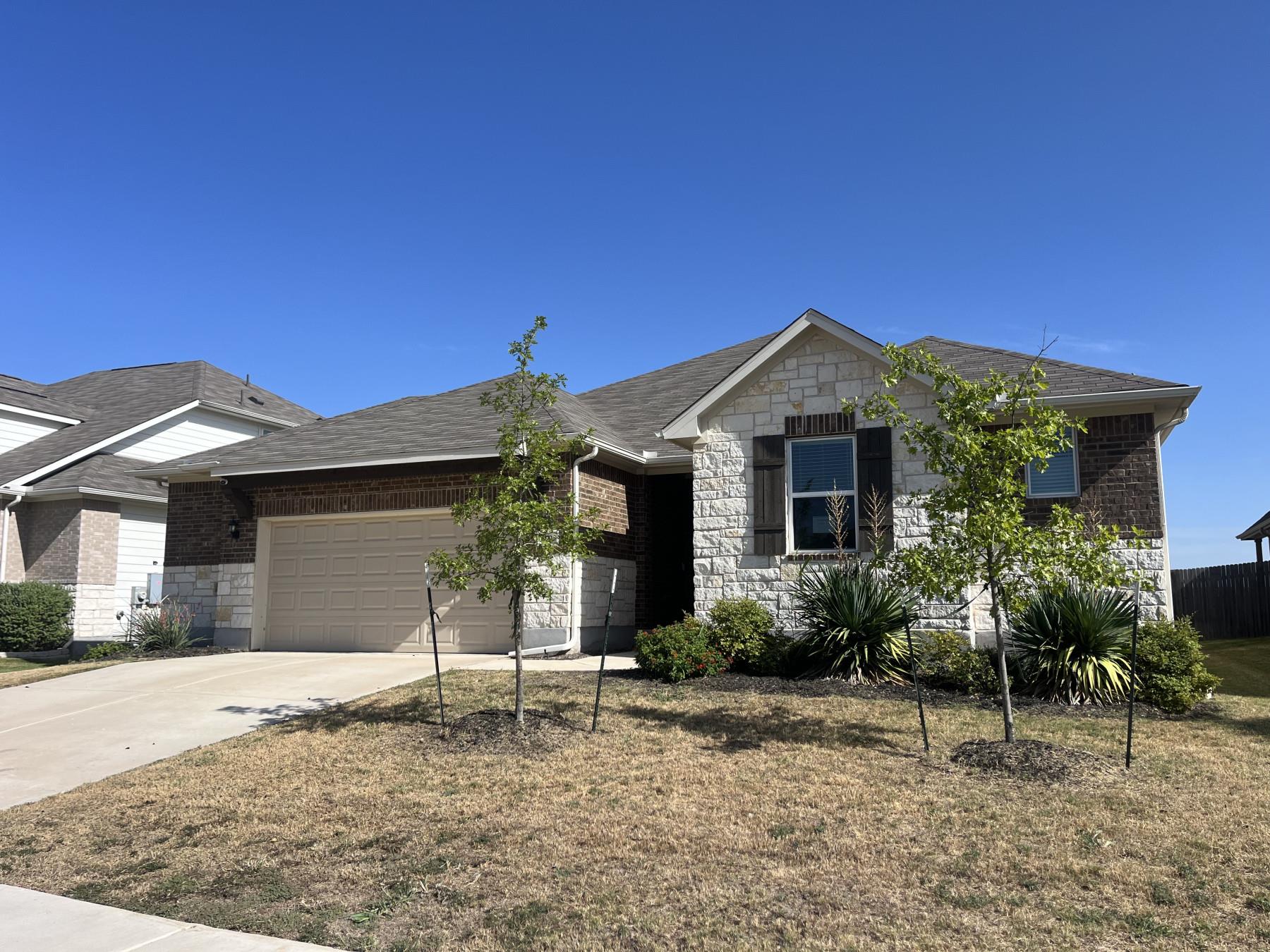 Masonry accents and a concrete driveway define th