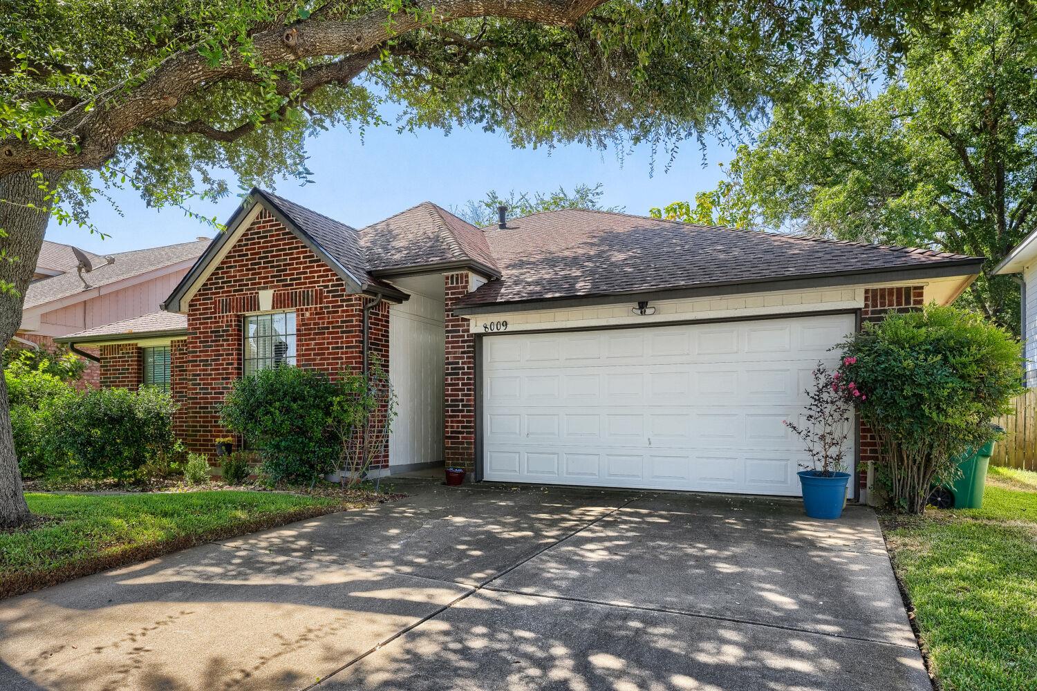 Mature shade trees frame a classic brick facade a