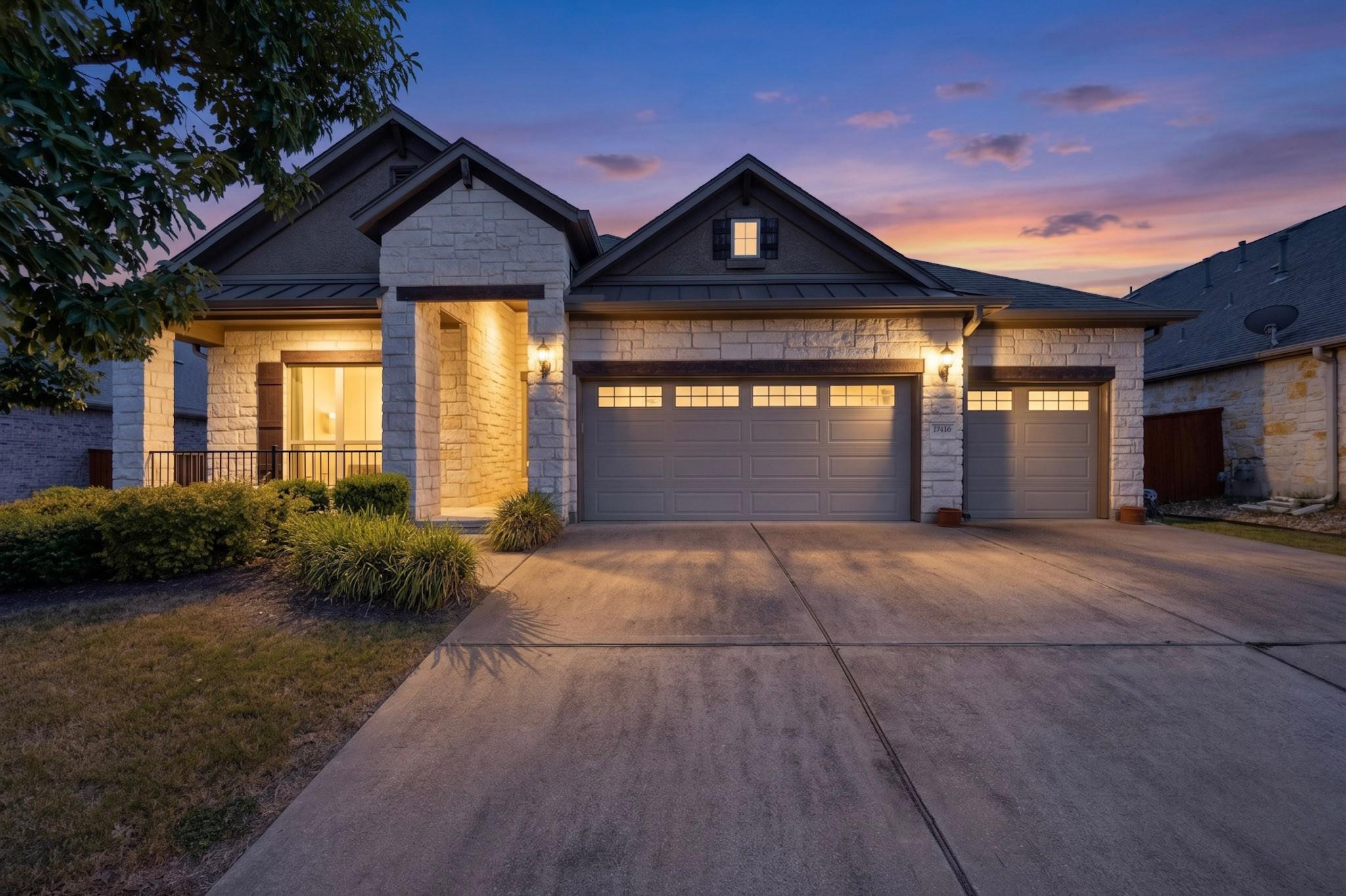 Textured stone siding and a wide concrete drivewa
