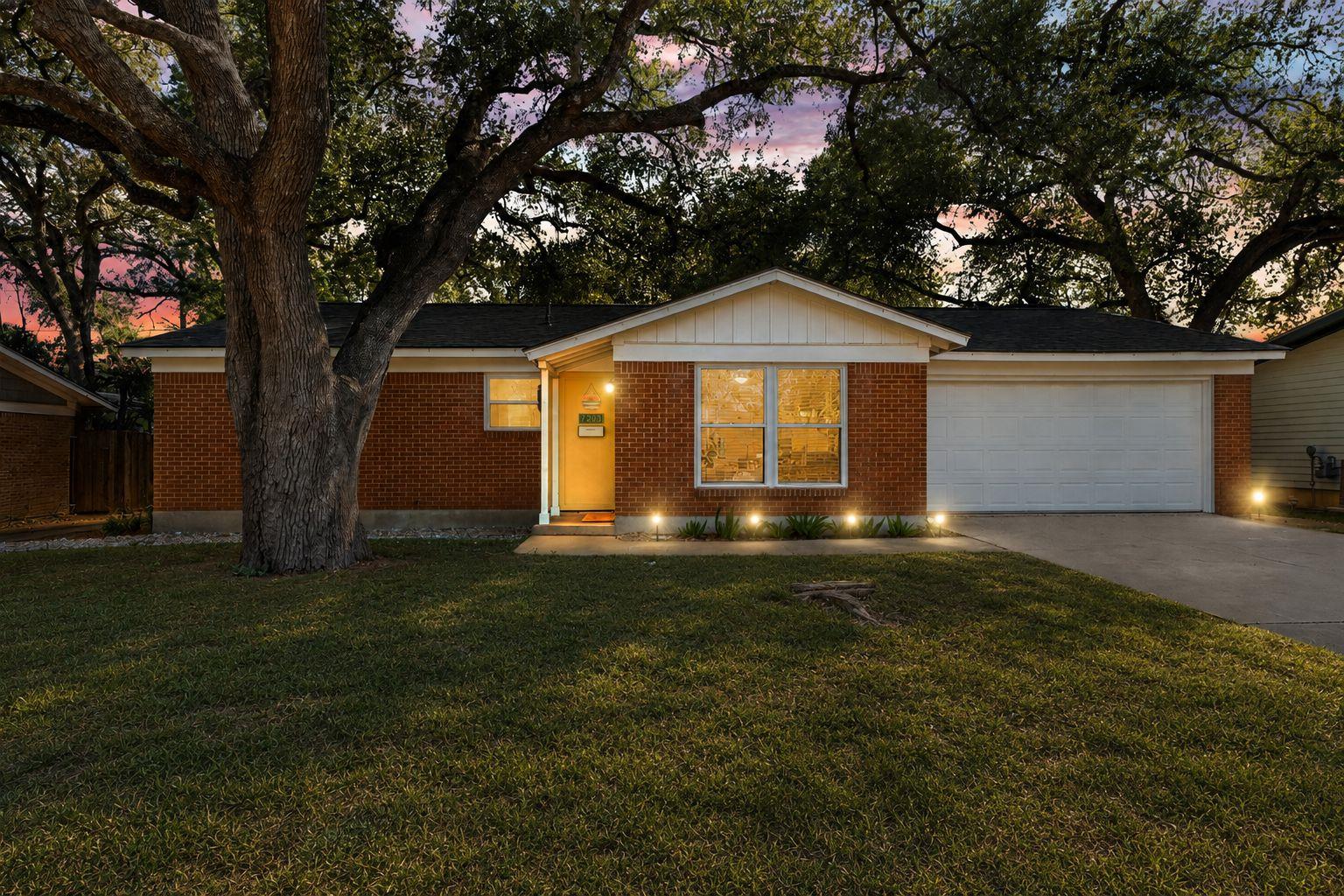 Mature shade trees frame this classic brick singl