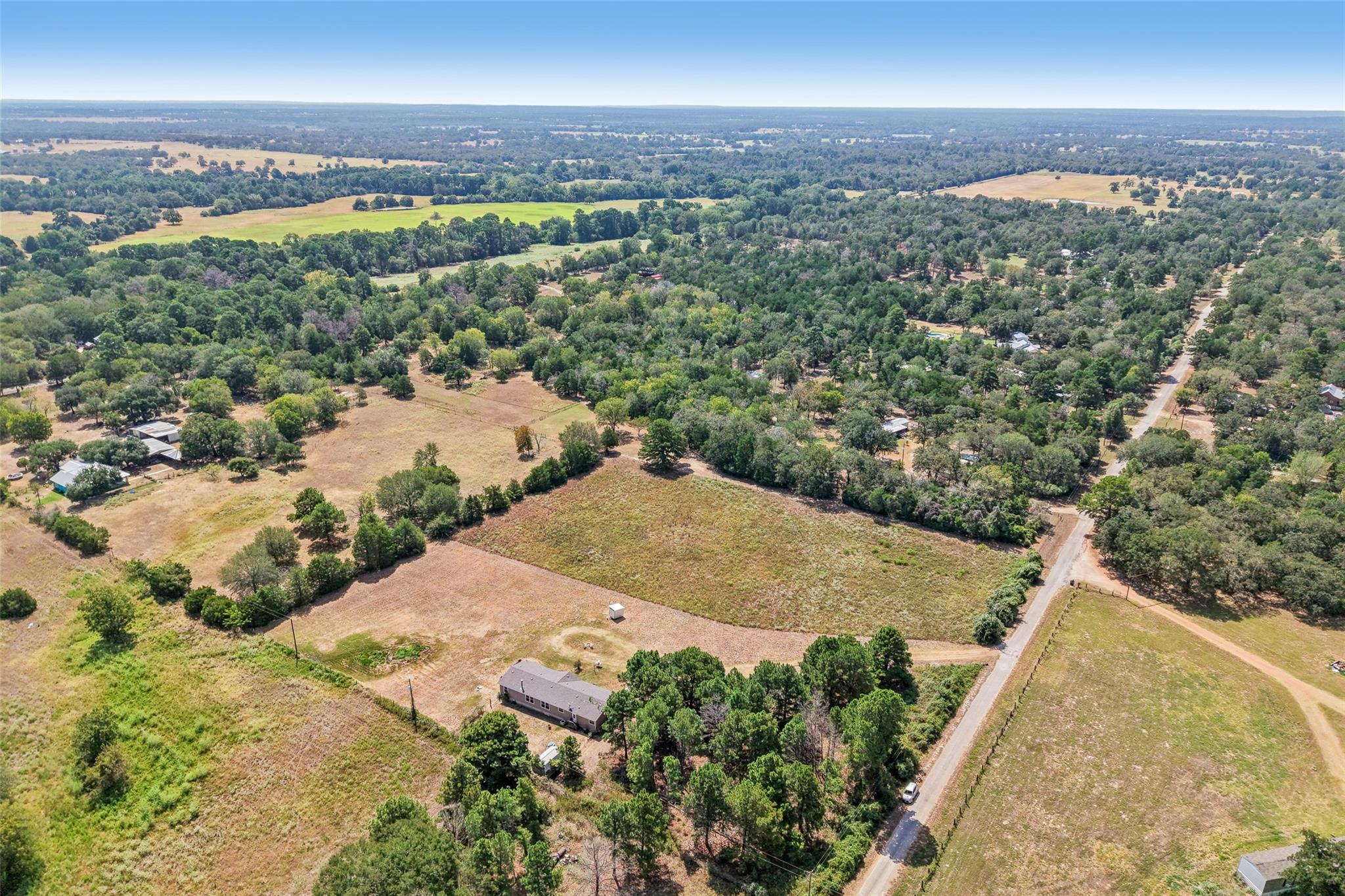 An expansive rural landscape features open pastur