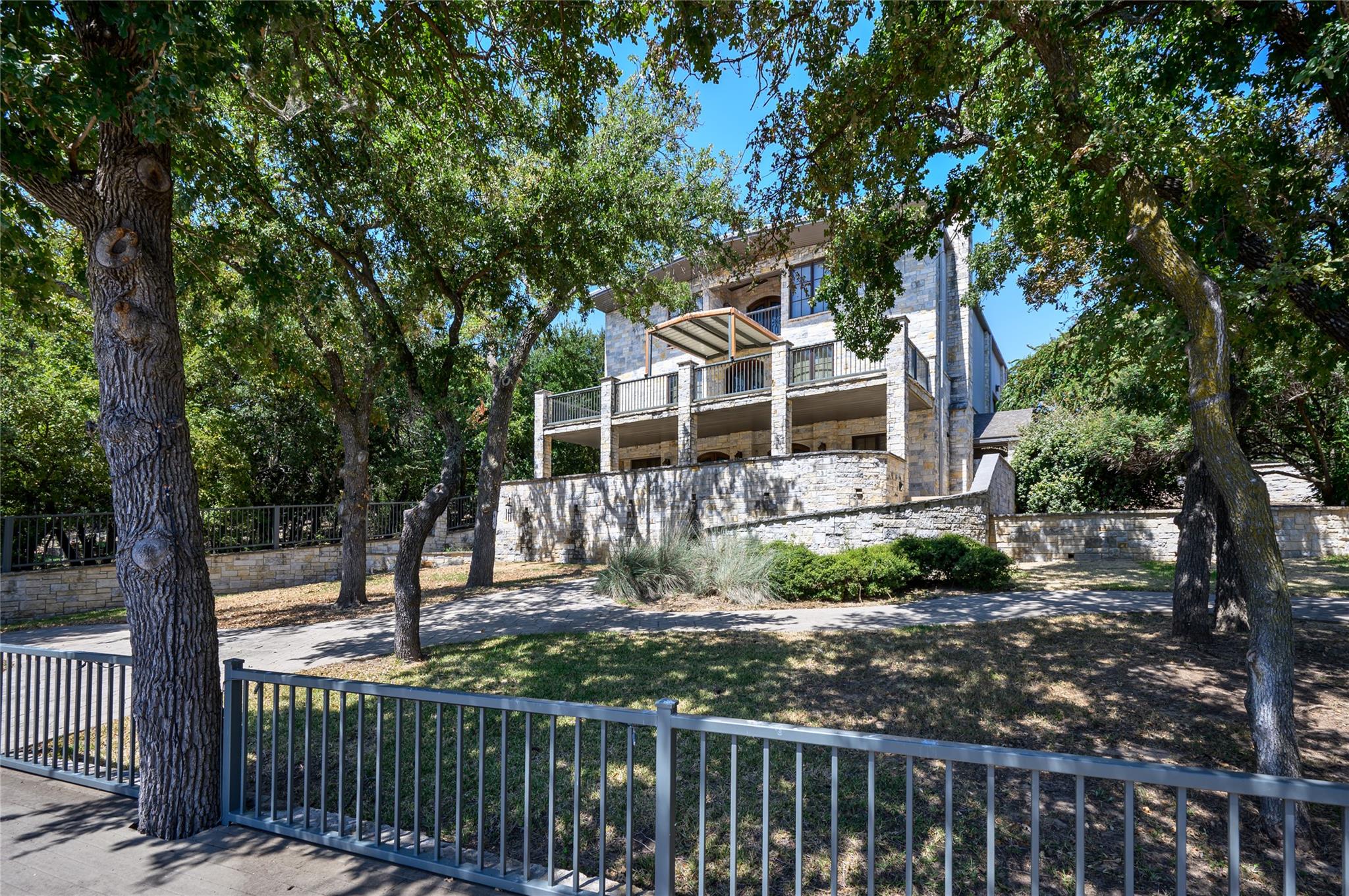 Mature trees shade a multi-level stone exterior f