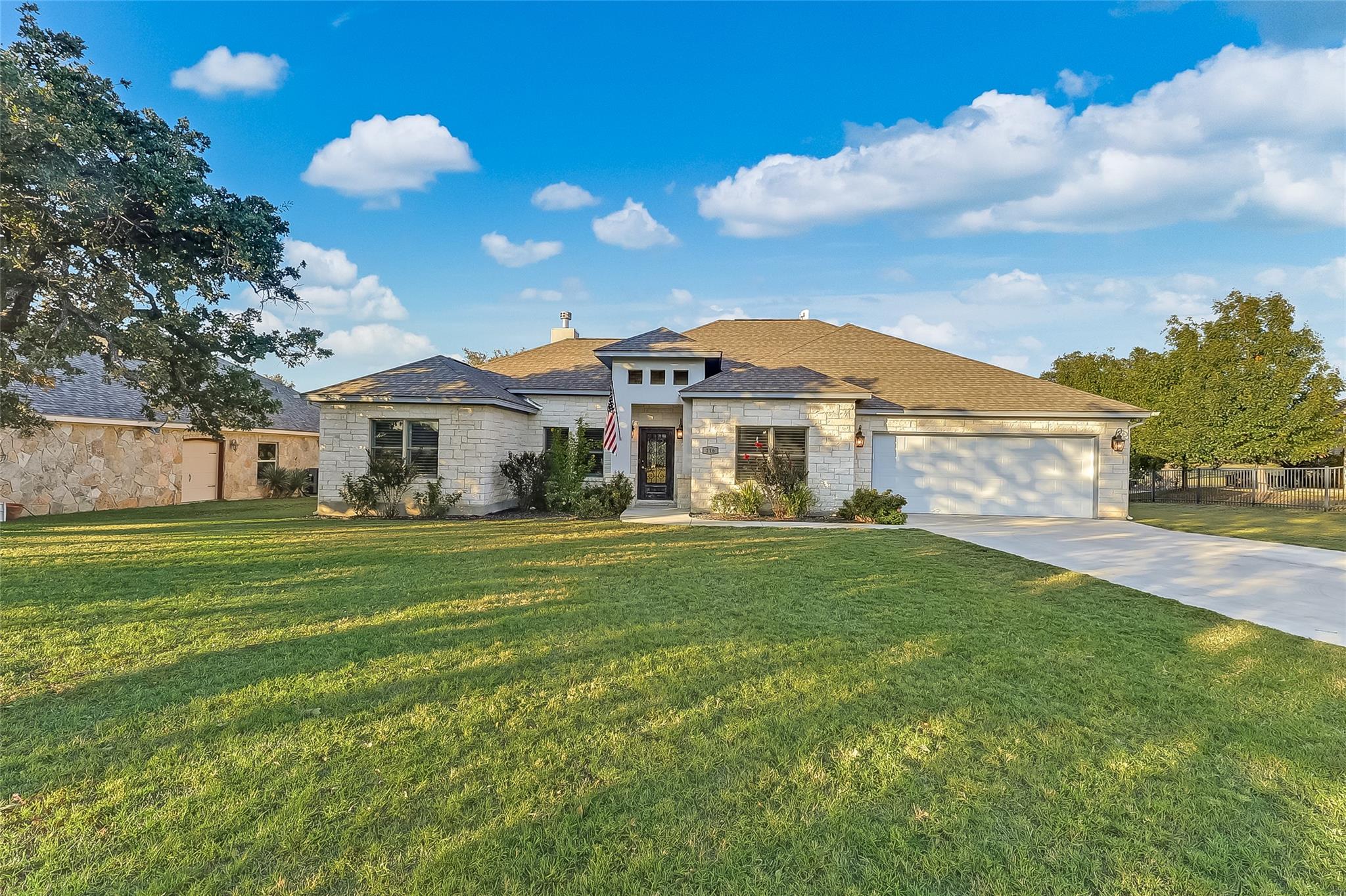 Limestone masonry and a wide concrete driveway de