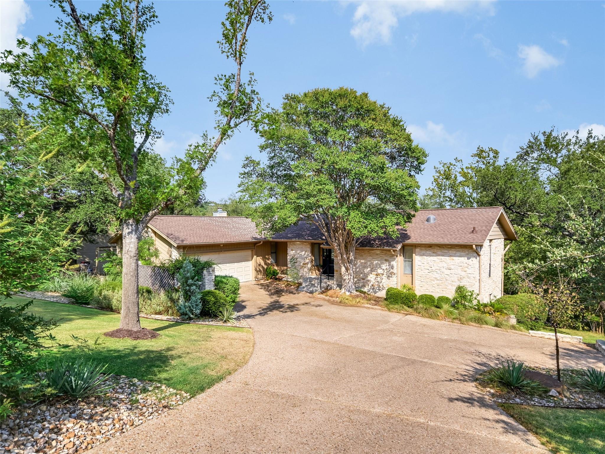 Mature trees frame the stone-accented facade and 