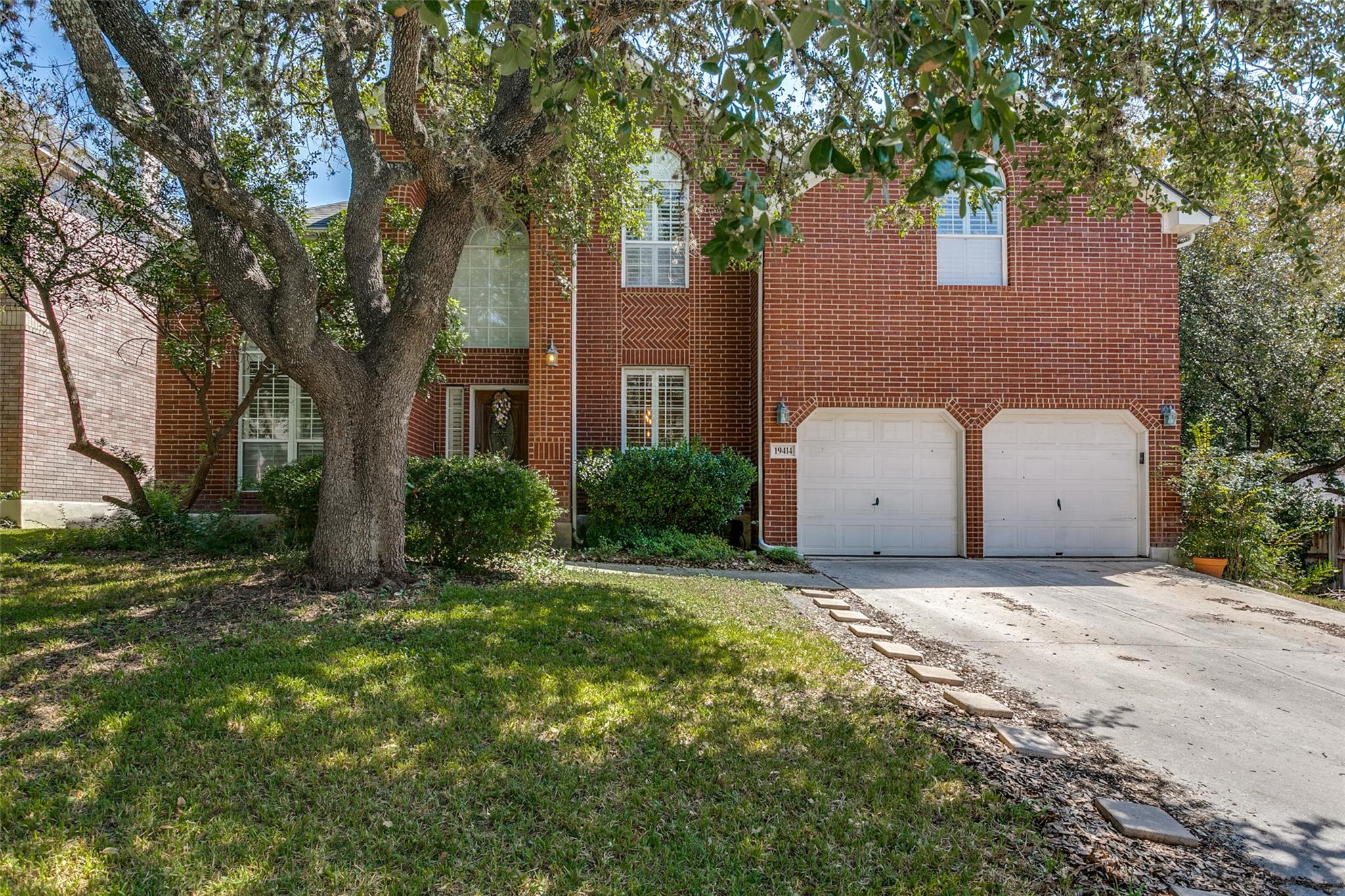 Mature trees shade a classic brick exterior featu