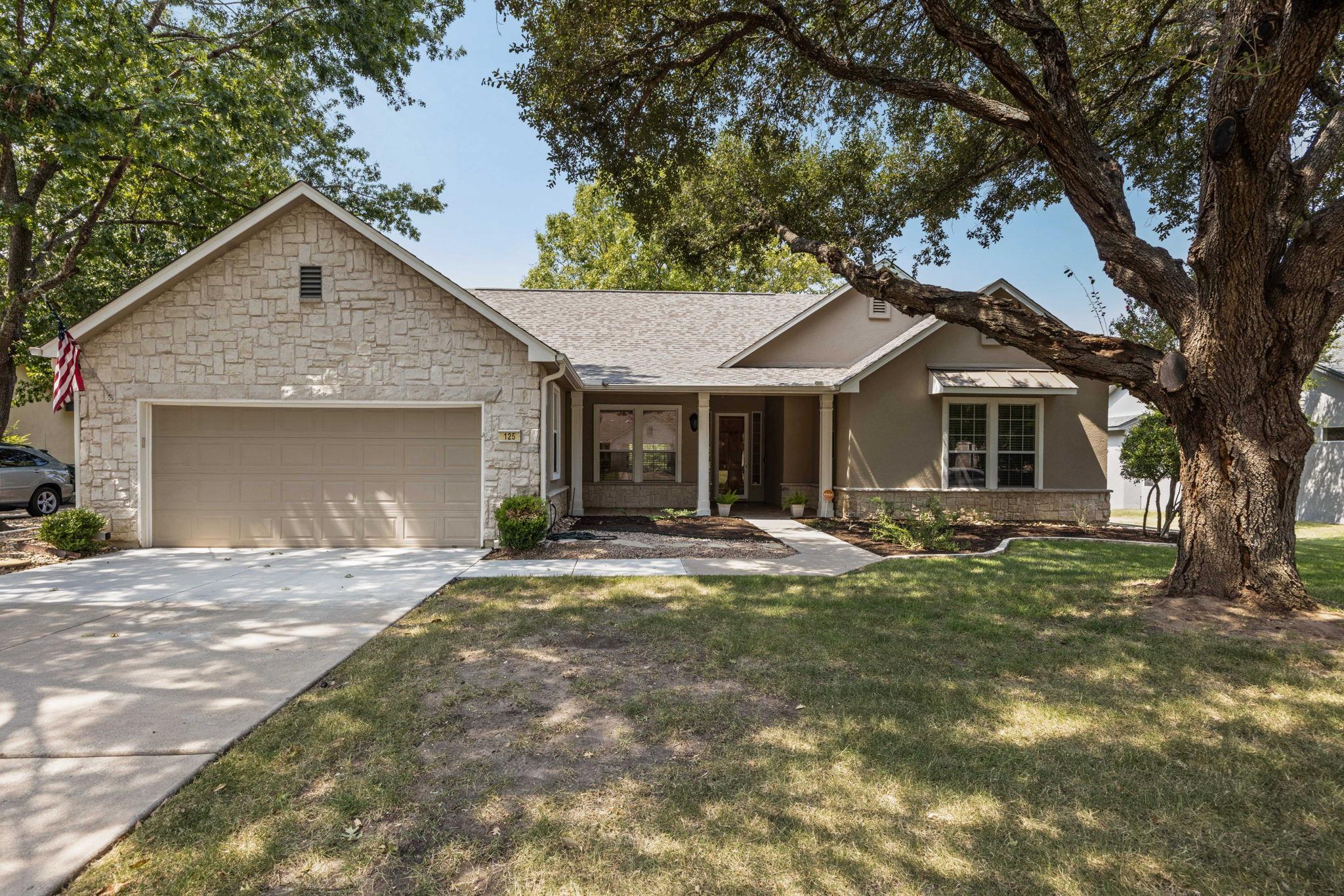 Mature shade trees frame this charming stone and 