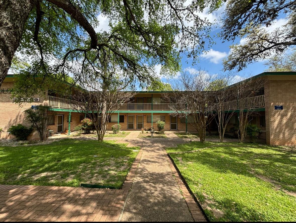 Mature shade trees frame a classic brick multi-un