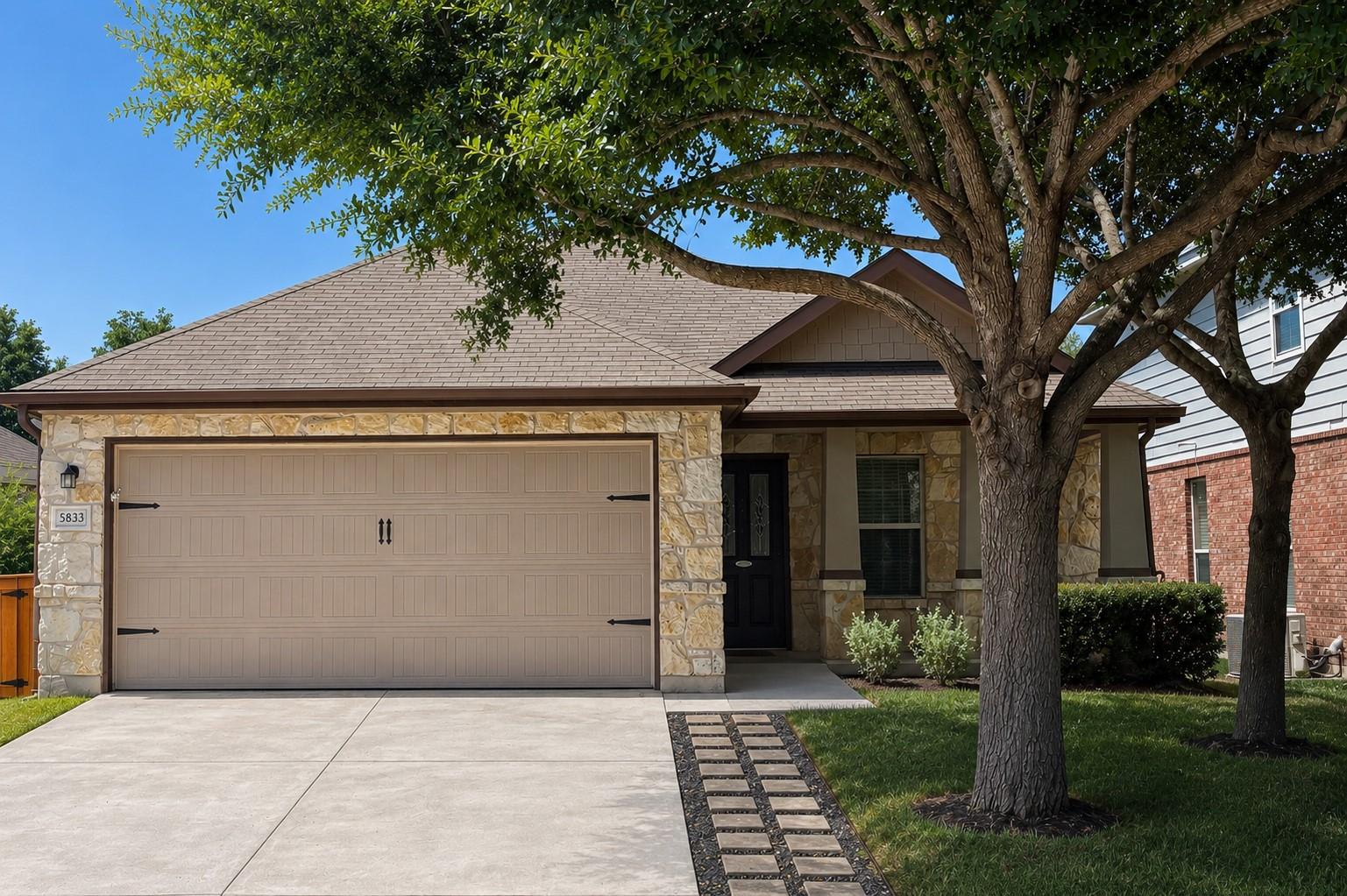 Mature trees shade the stone and siding exterior 