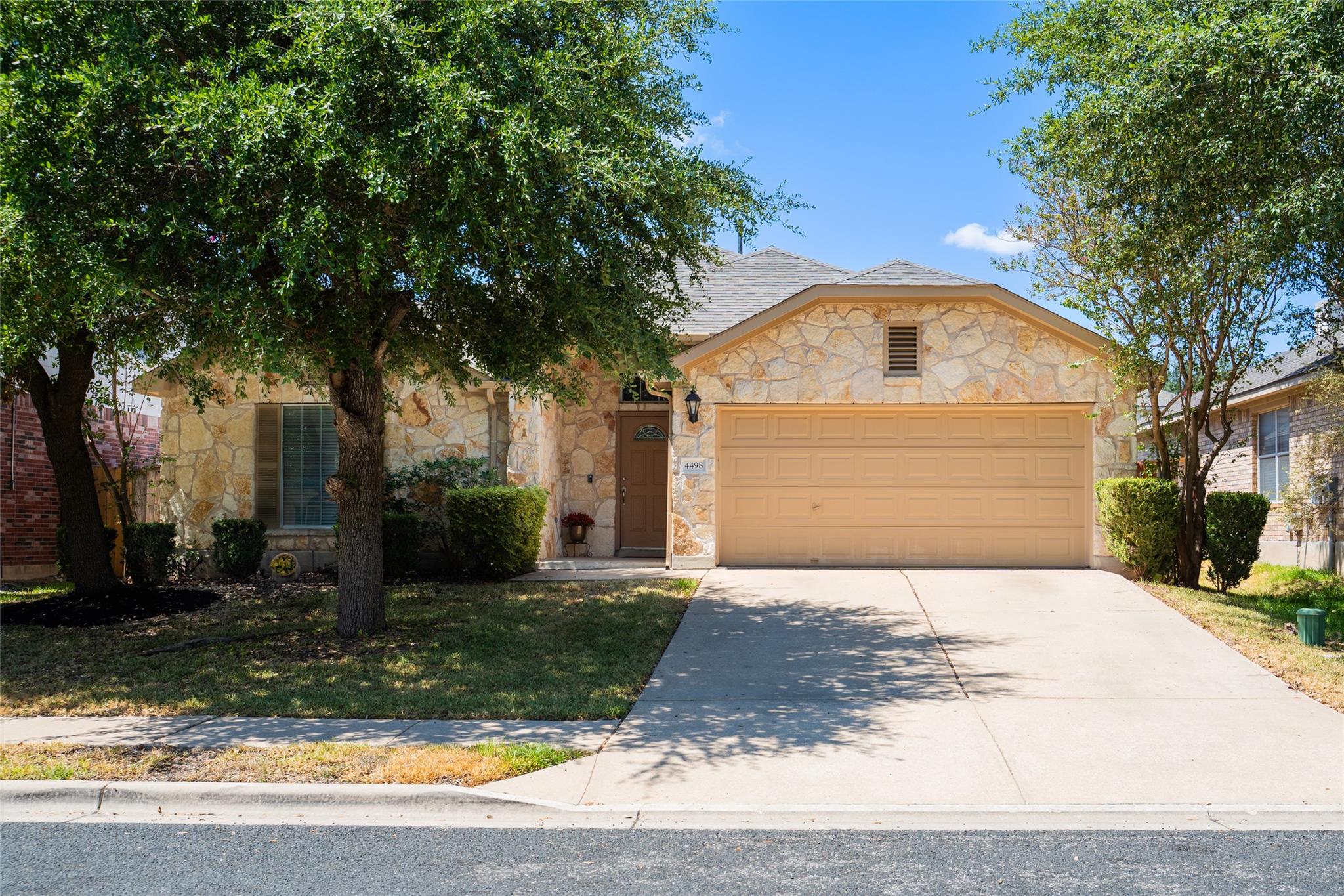 Mature trees shade a classic stone exterior featu