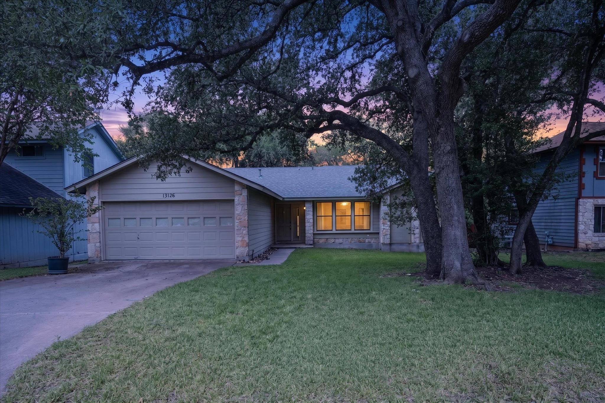Mature oak trees shade the front lawn and paved d