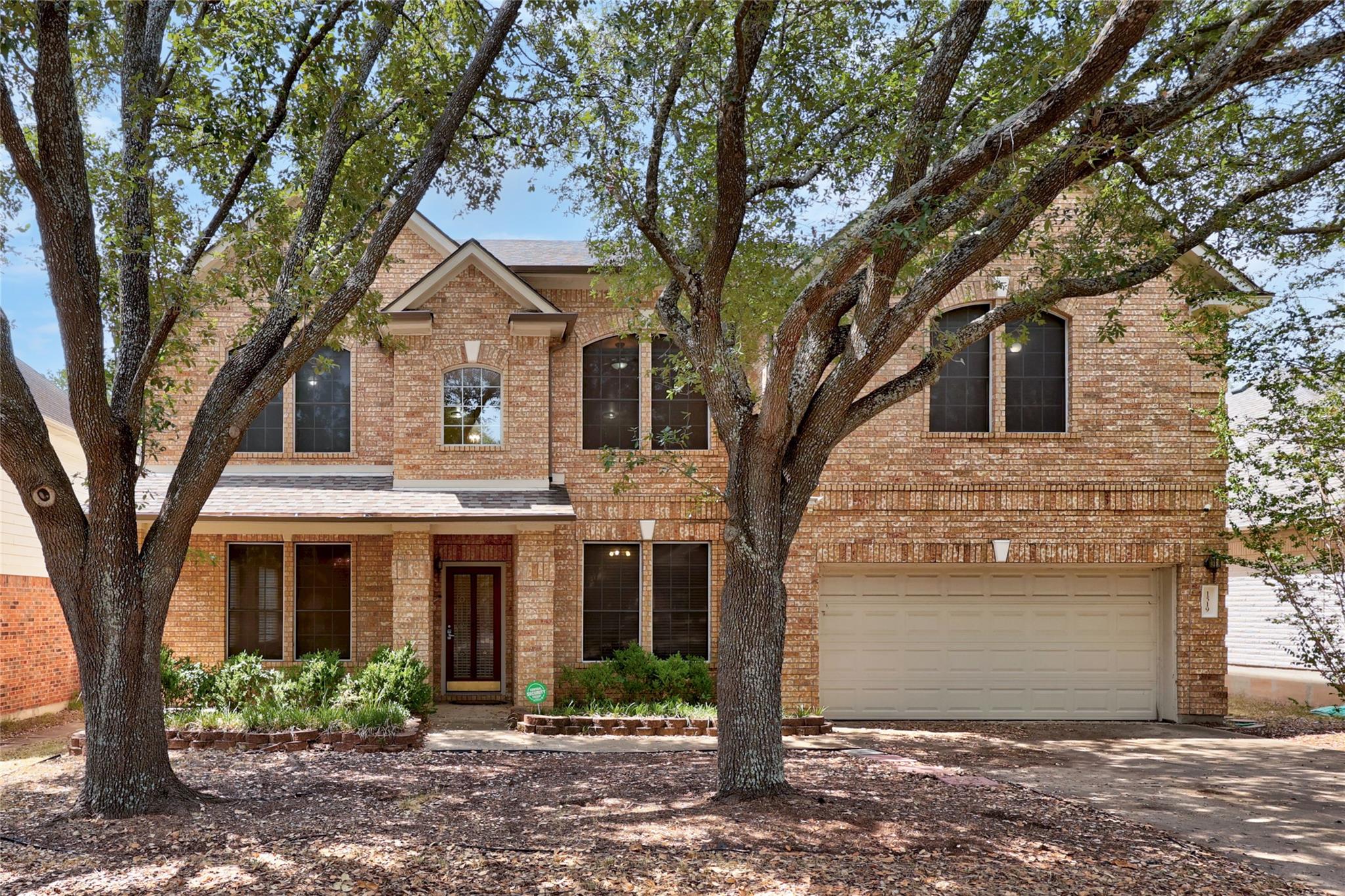 Mature shade trees frame the classic brick facade