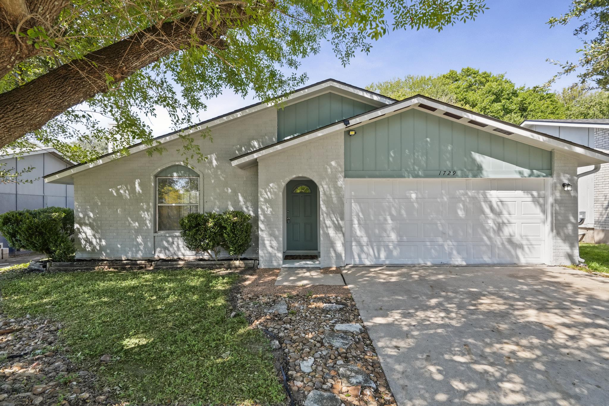 Mature trees shade a welcoming paved driveway lea