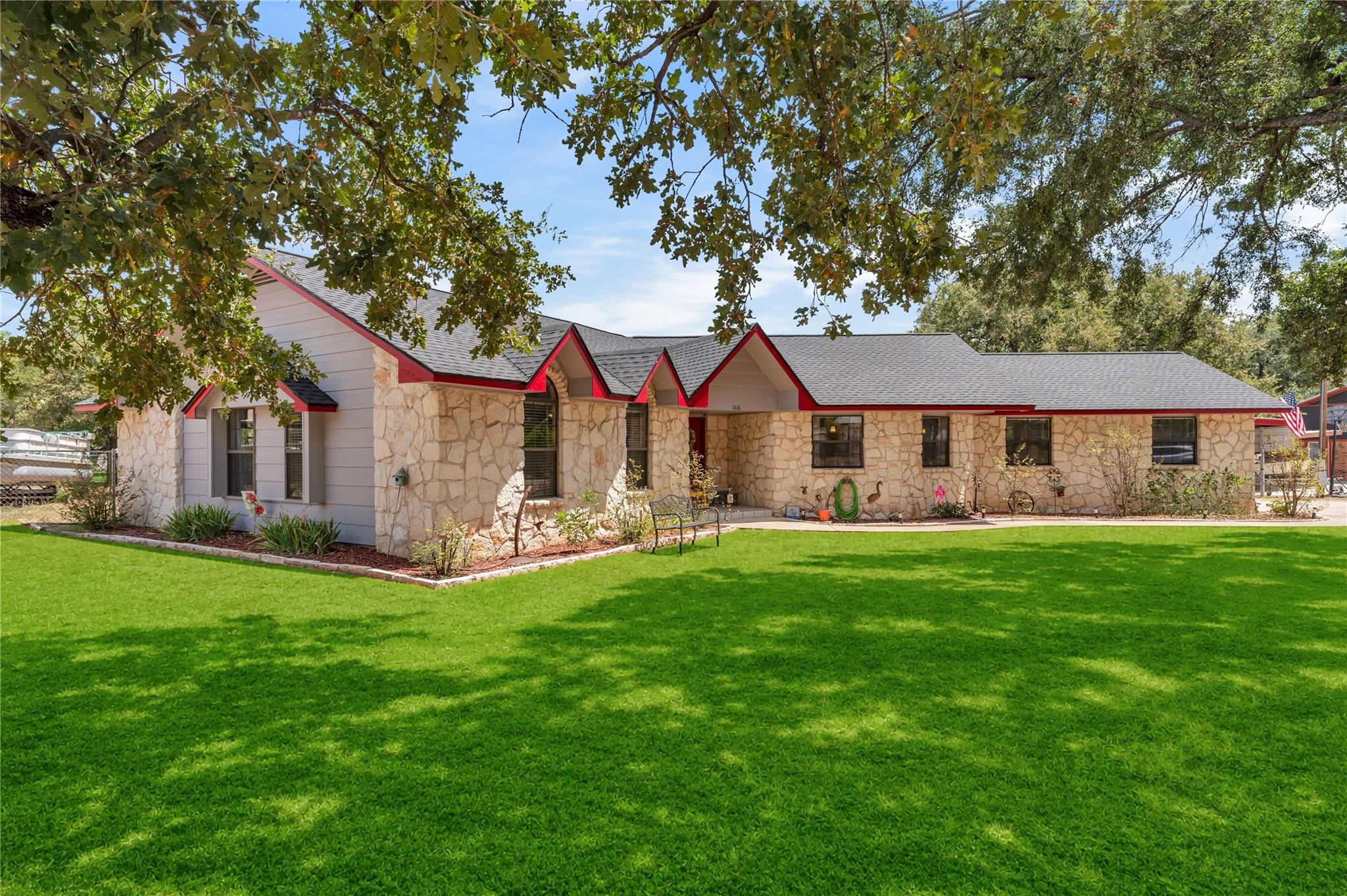 Shade trees frame a manicured lawn leading to thi