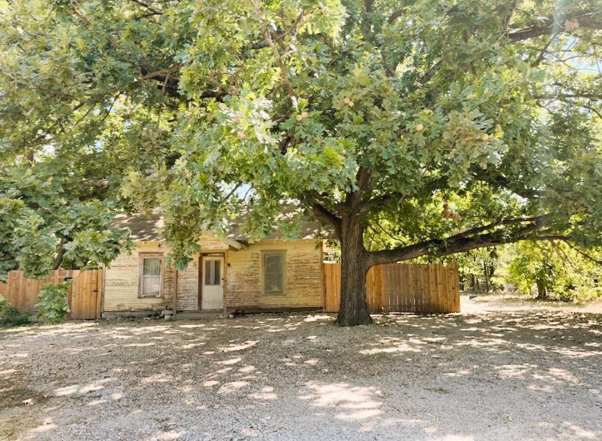 Mature shade trees frame this rustic single-story