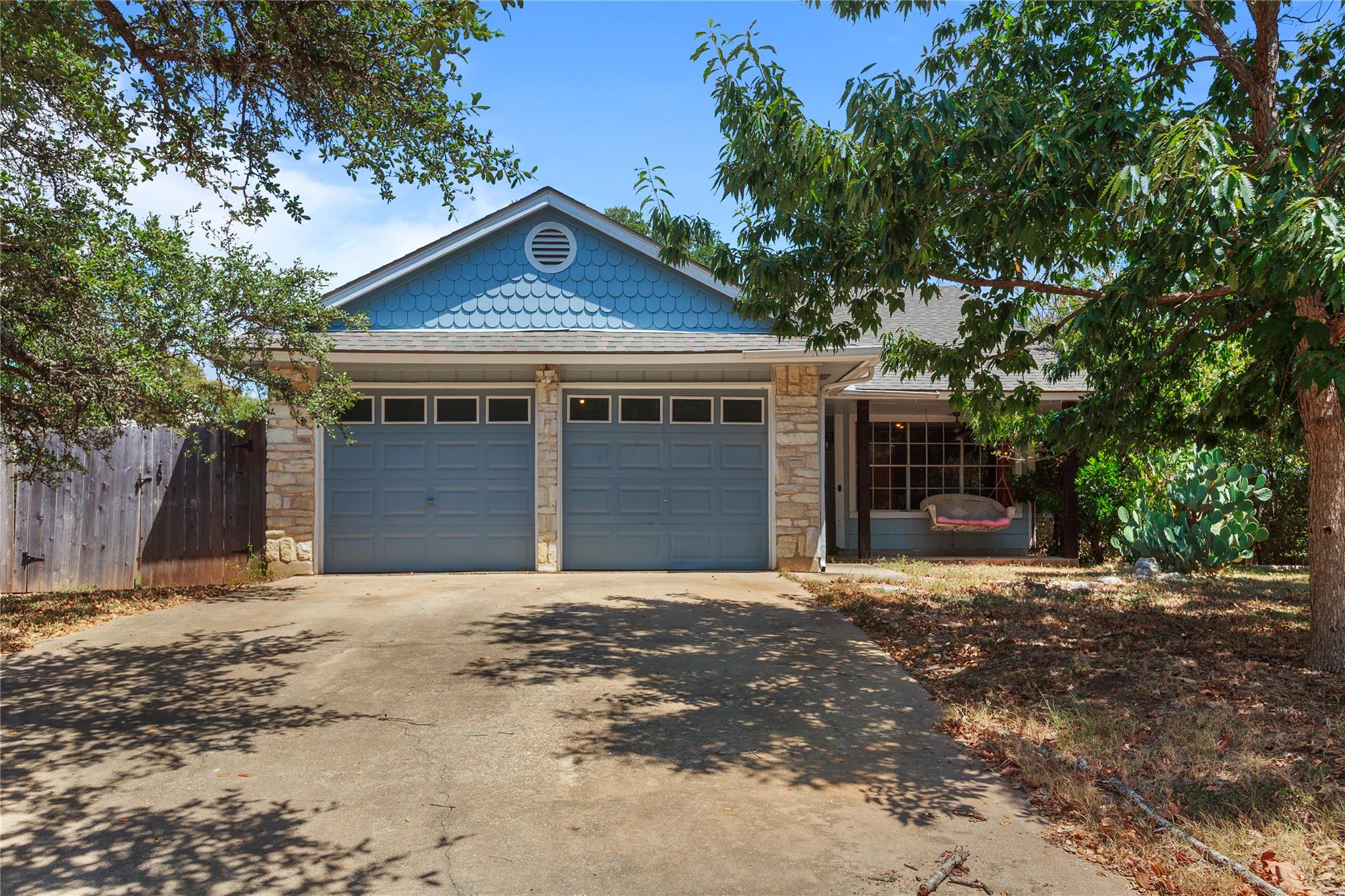 Mature trees shade the driveway leading to a two-