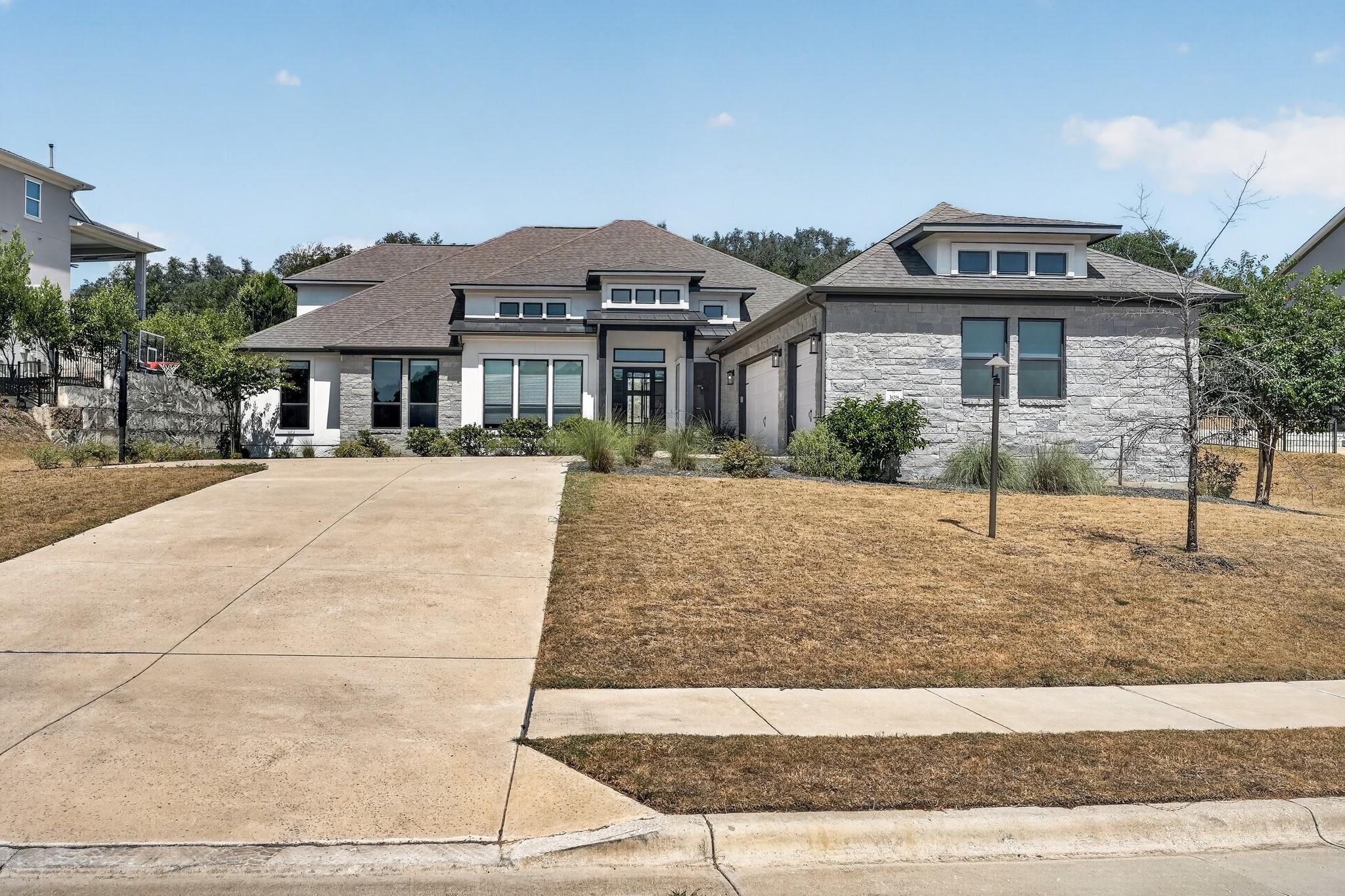 A spacious driveway leads to this modern stone an