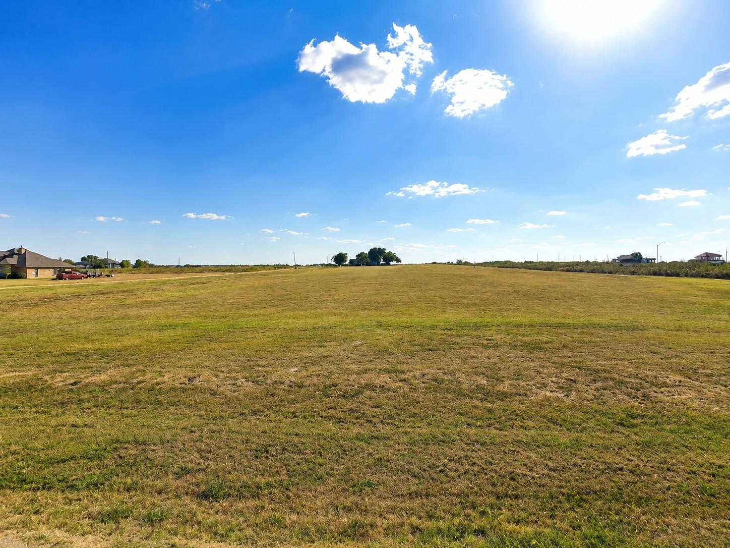 A vast open pasture stretches out beneath a wide 