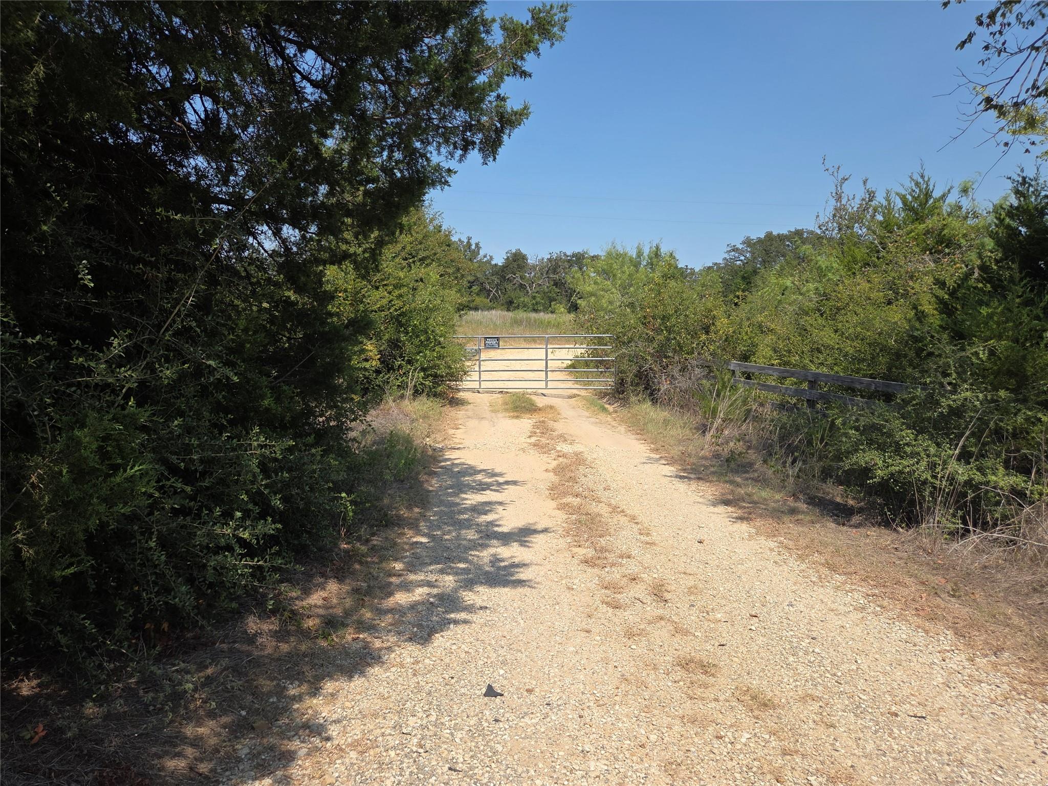 A long gravel driveway leads to a gated entrance 