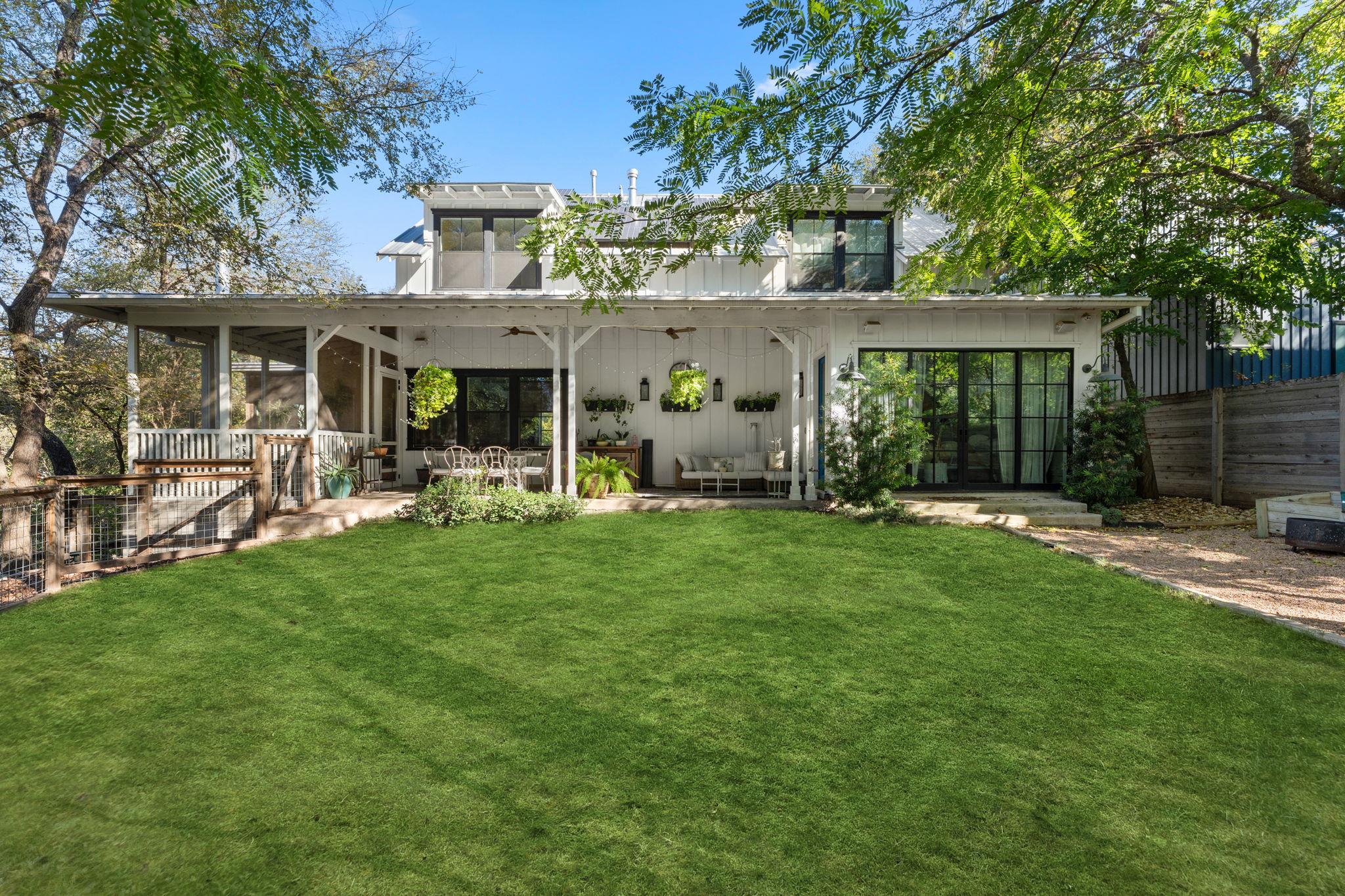 Mature trees frame a spacious lawn and a covered 