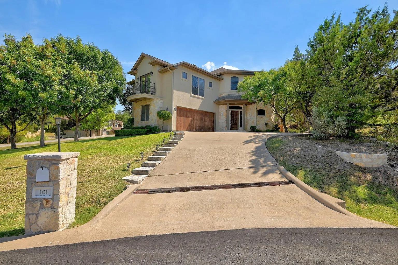A long concrete driveway ascends to an elegant mu