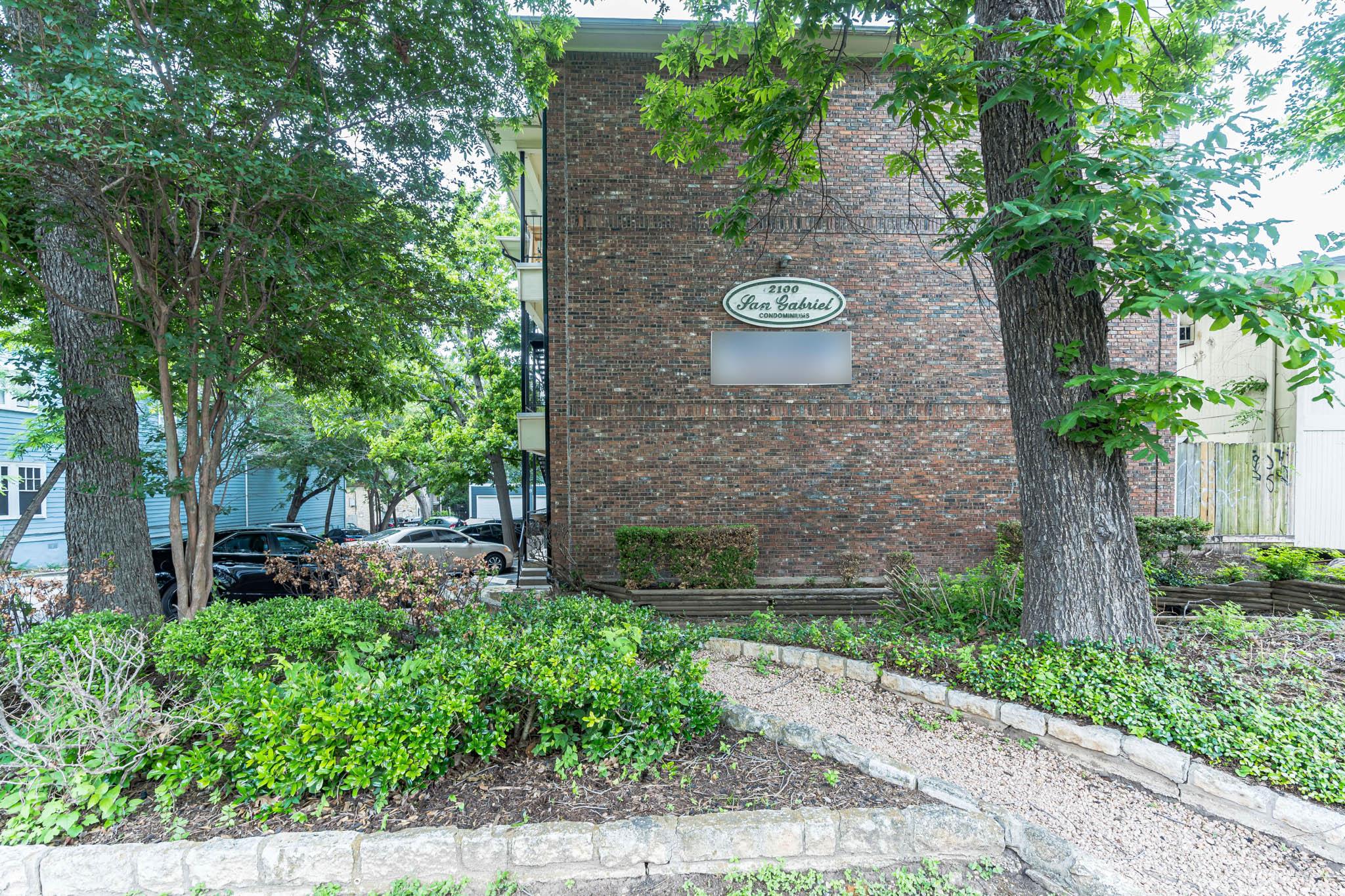 Mature trees and neat brickwork frame the exterio