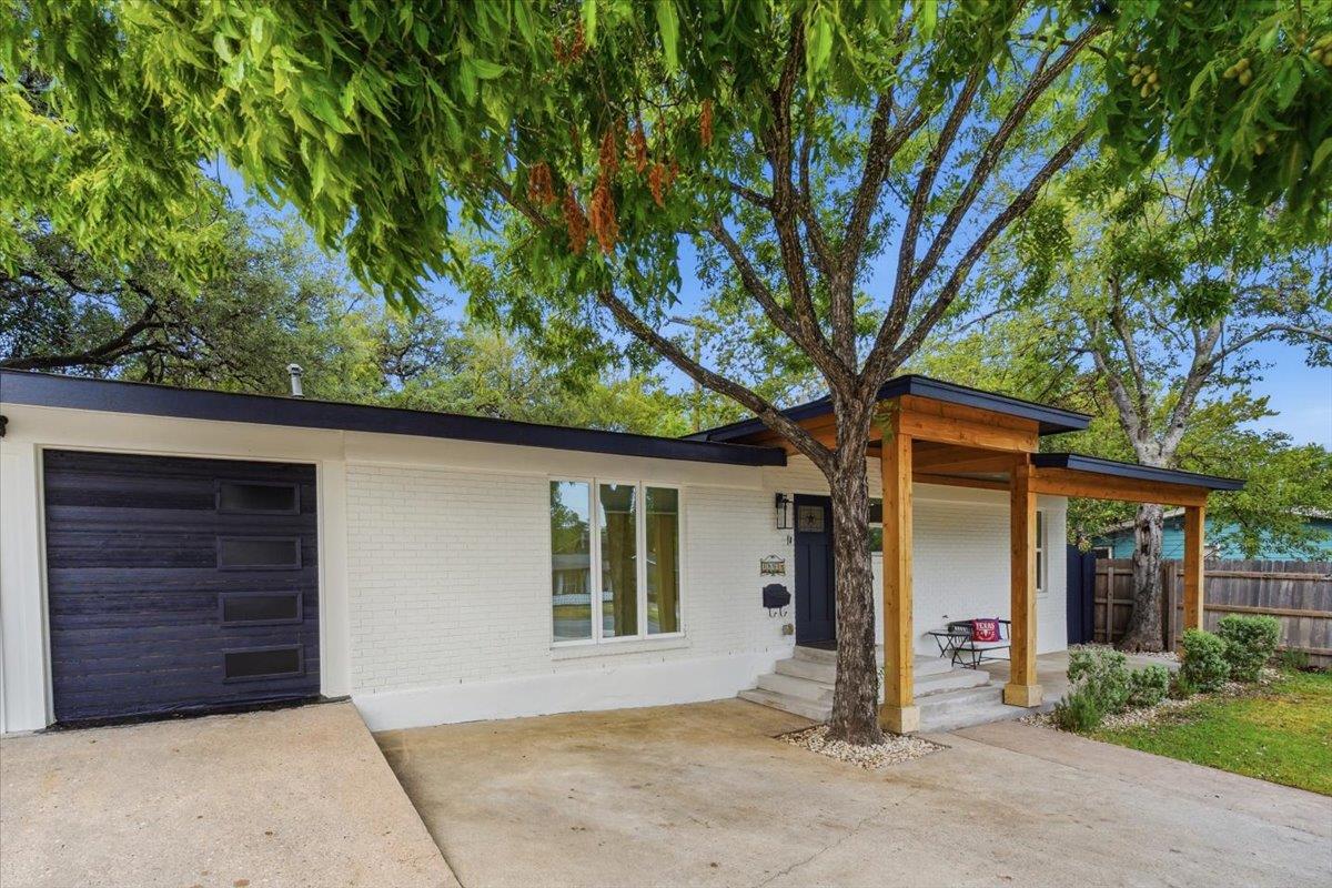 Mature trees shade a welcoming front porch set ag