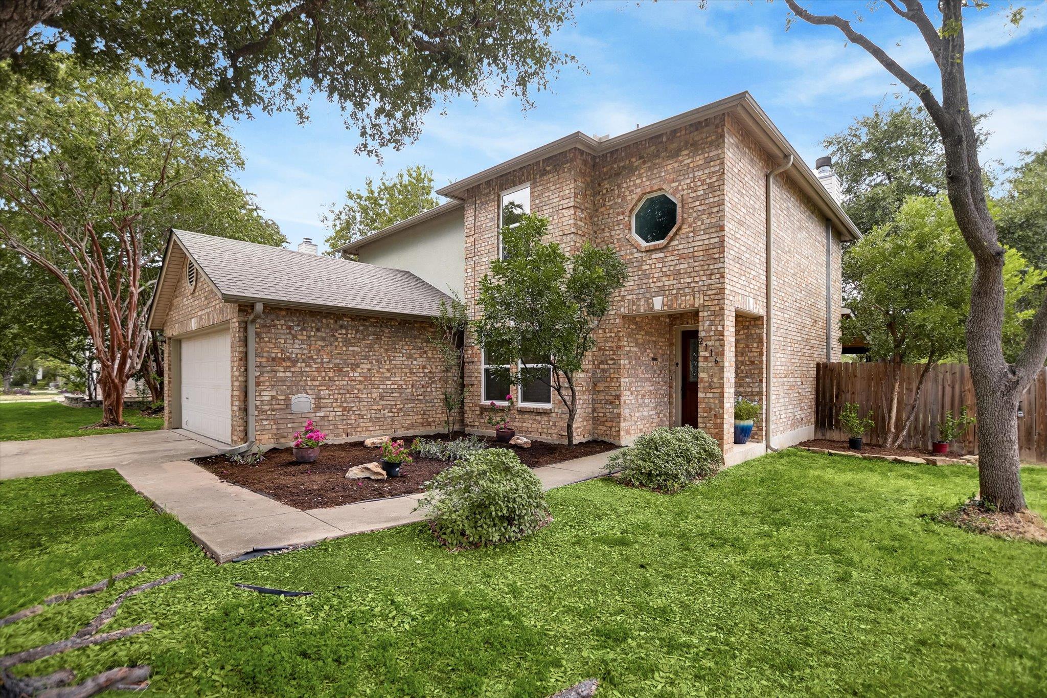 Mature trees frame a classic two-story brick exte