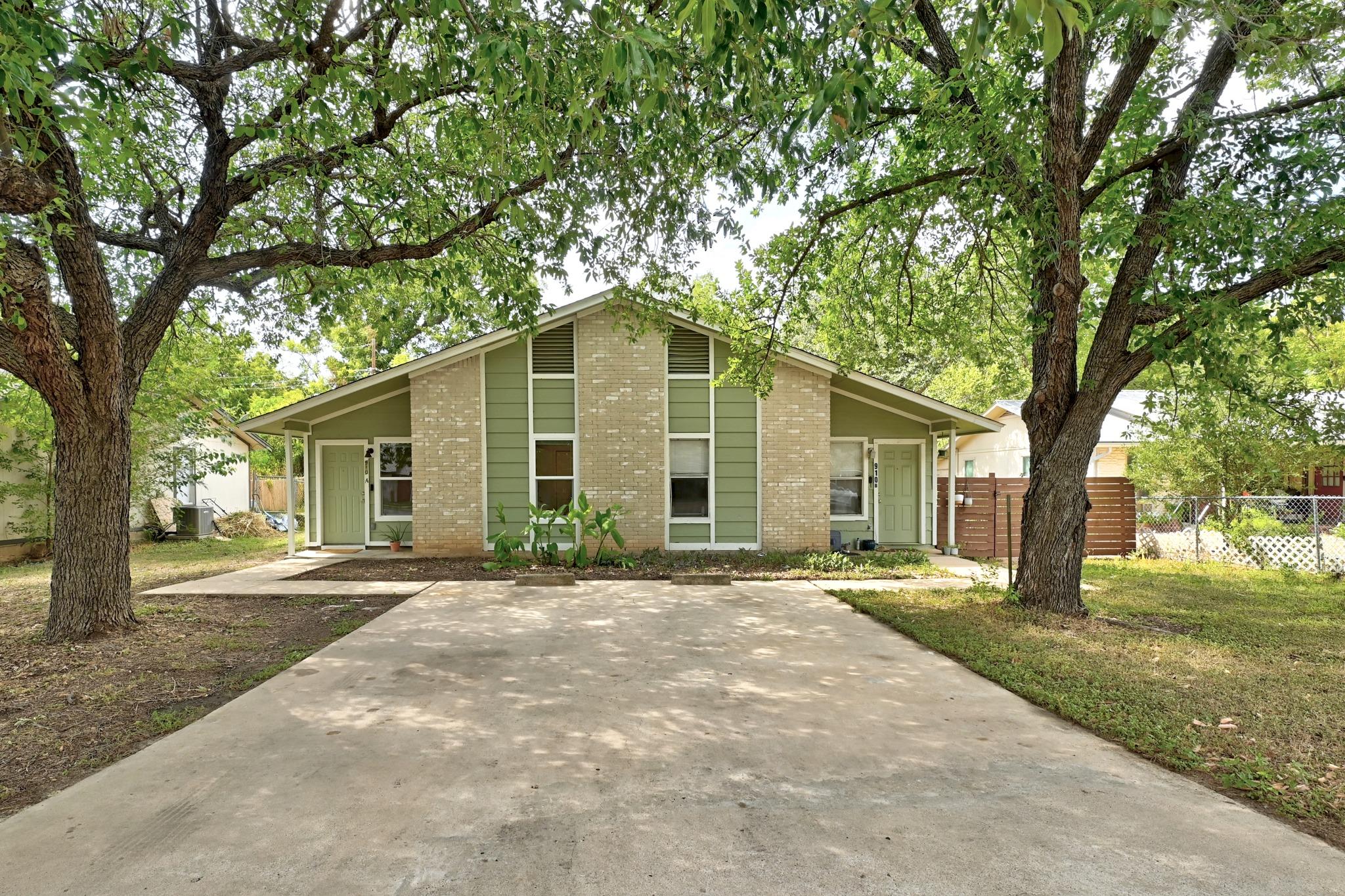 Mature shade trees frame a concrete driveway lead