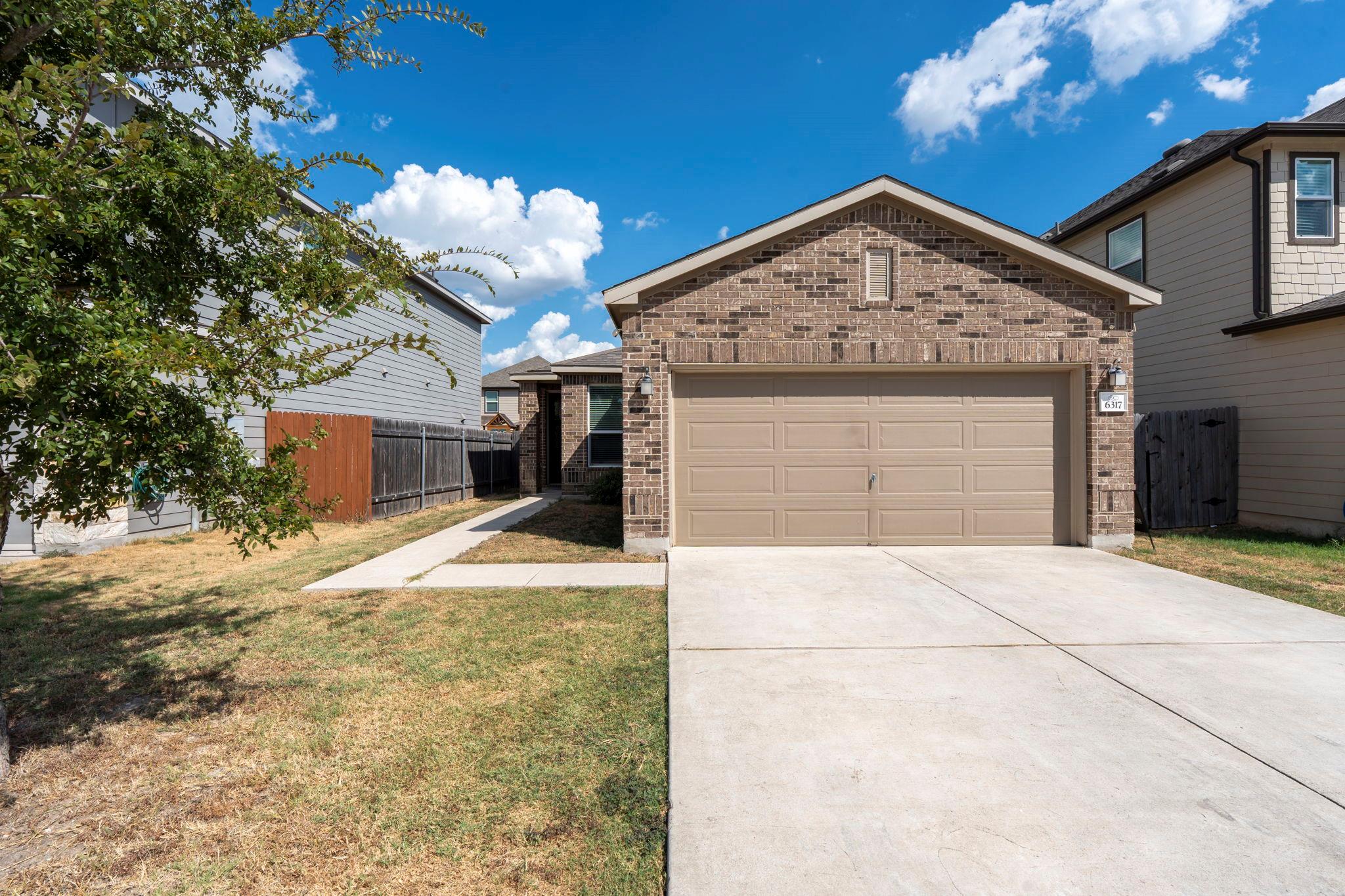 Brick cladding and a concrete driveway define thi