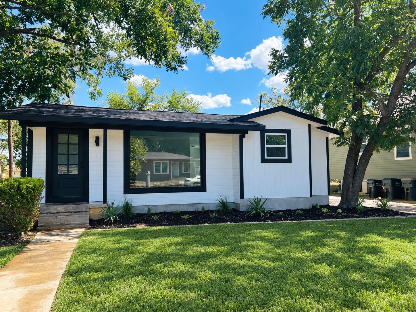 Mature trees shade a manicured front lawn leading