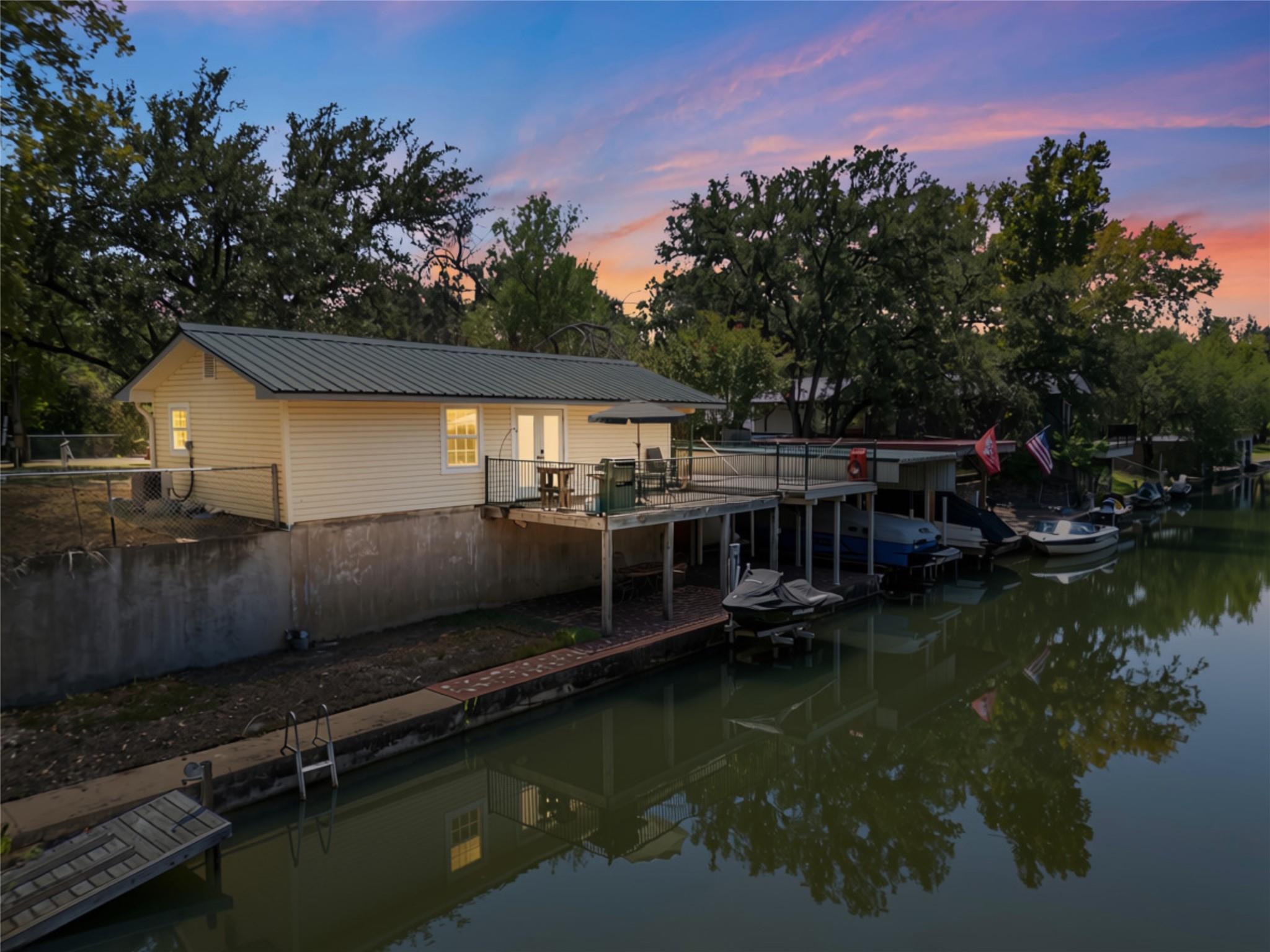 A metal-roofed waterfront cottage stands above a 