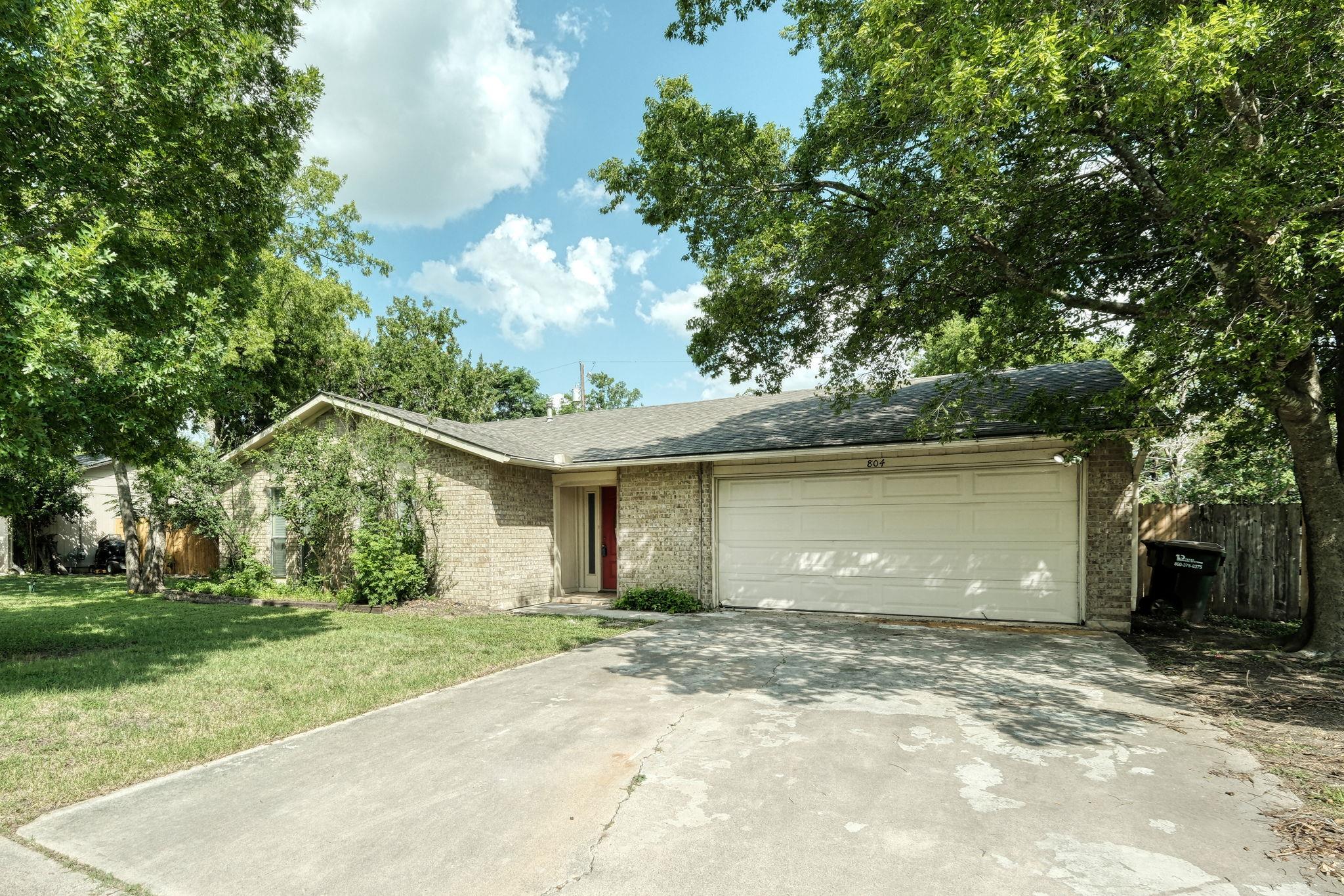 Mature trees shade a classic brick facade with an