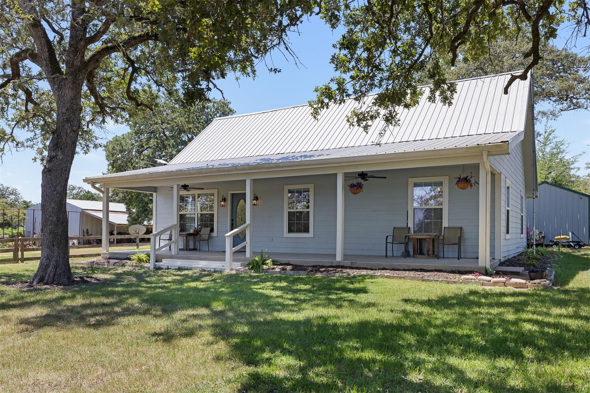 Mature trees shade a welcoming front porch set be
