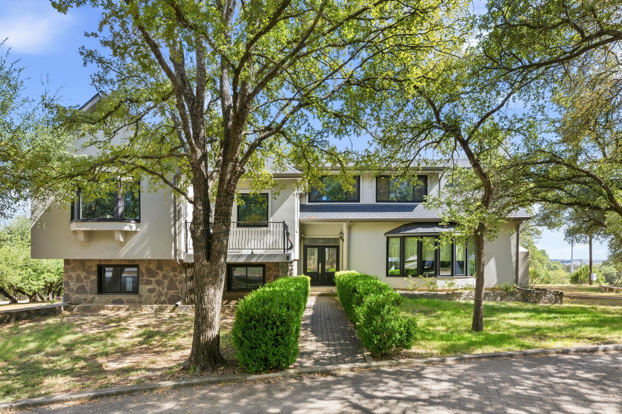 Mature trees shade the stone and stucco facade of