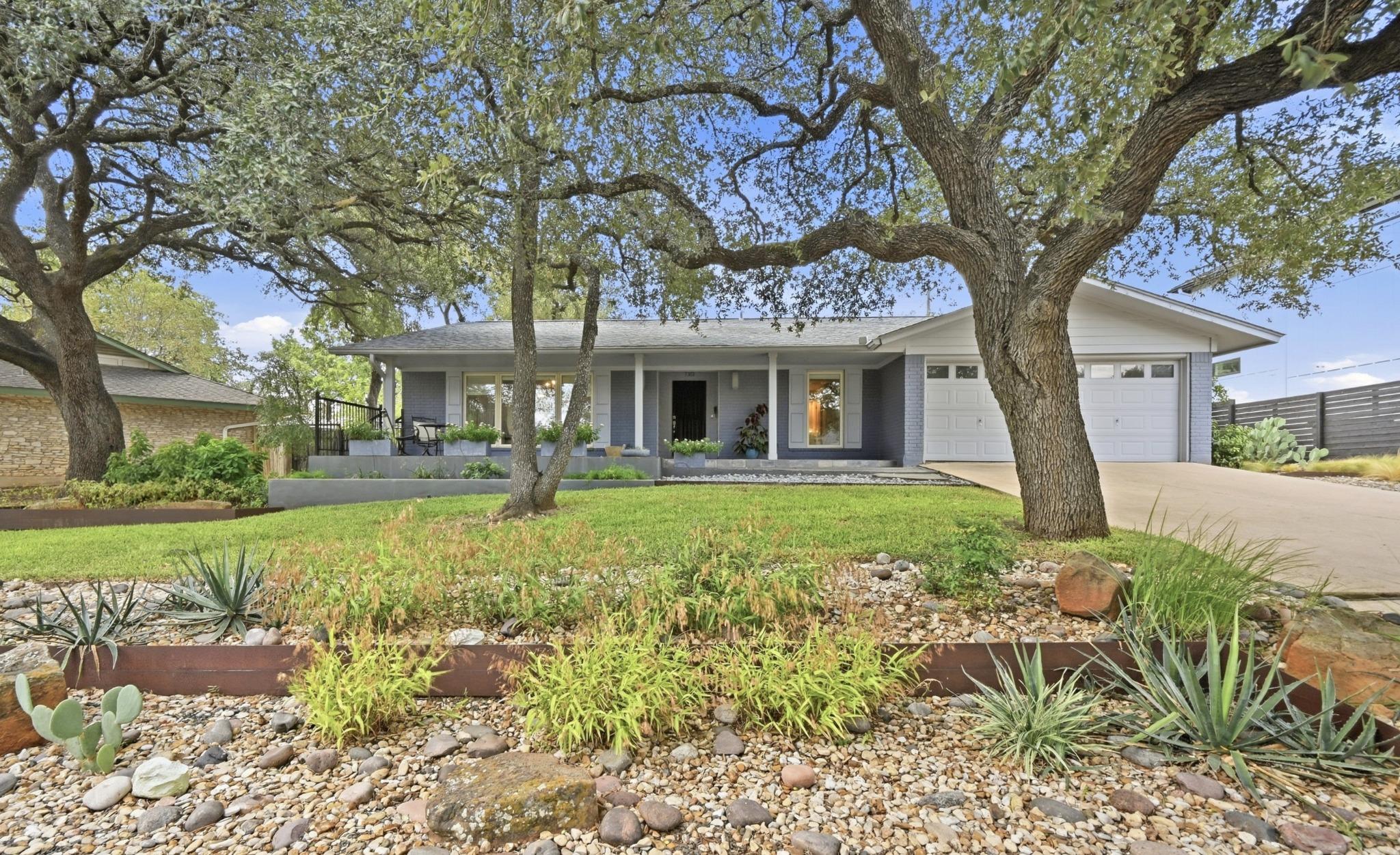 Mature oak trees frame the classic single-story f