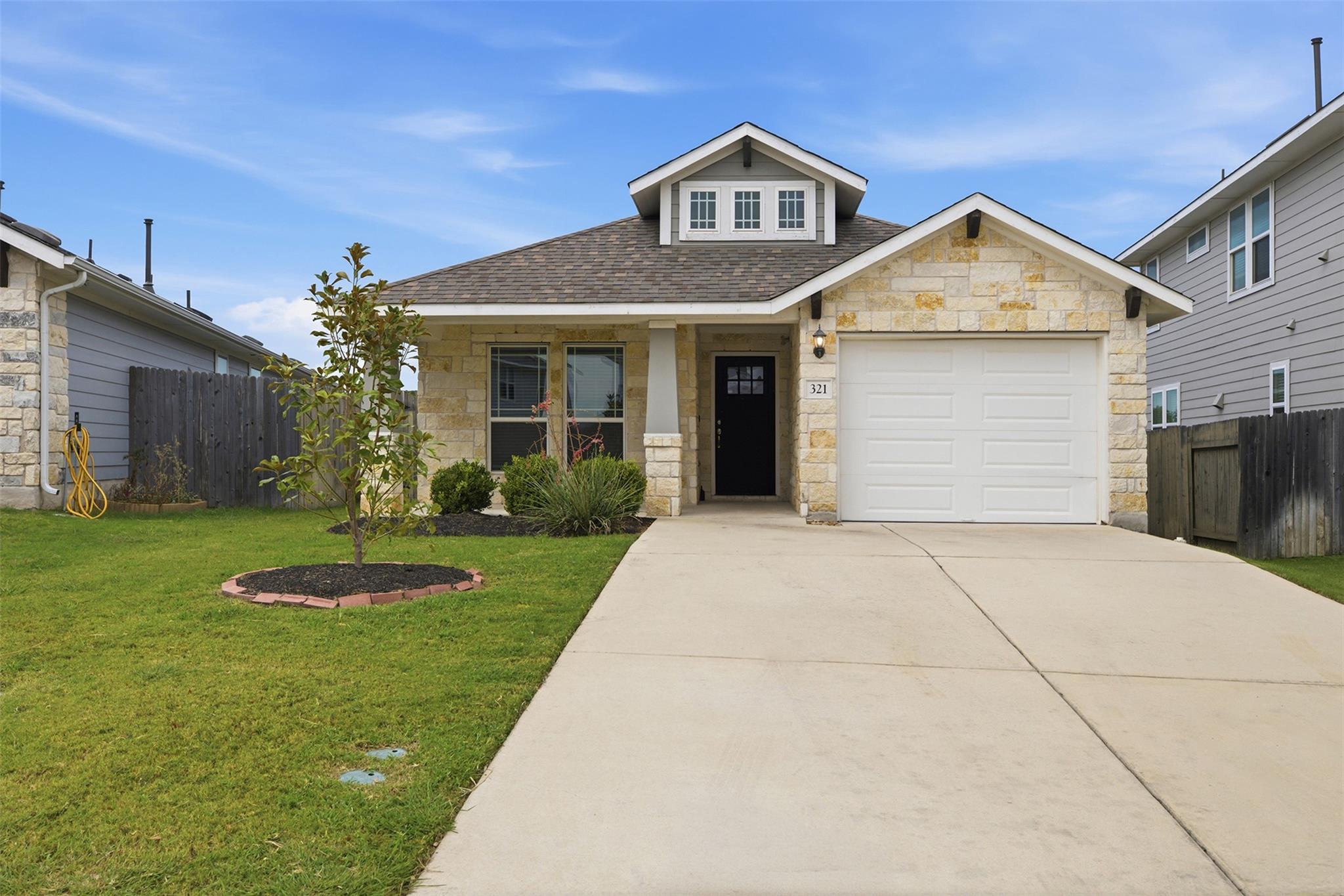 Textured stone siding and a neat concrete drivewa