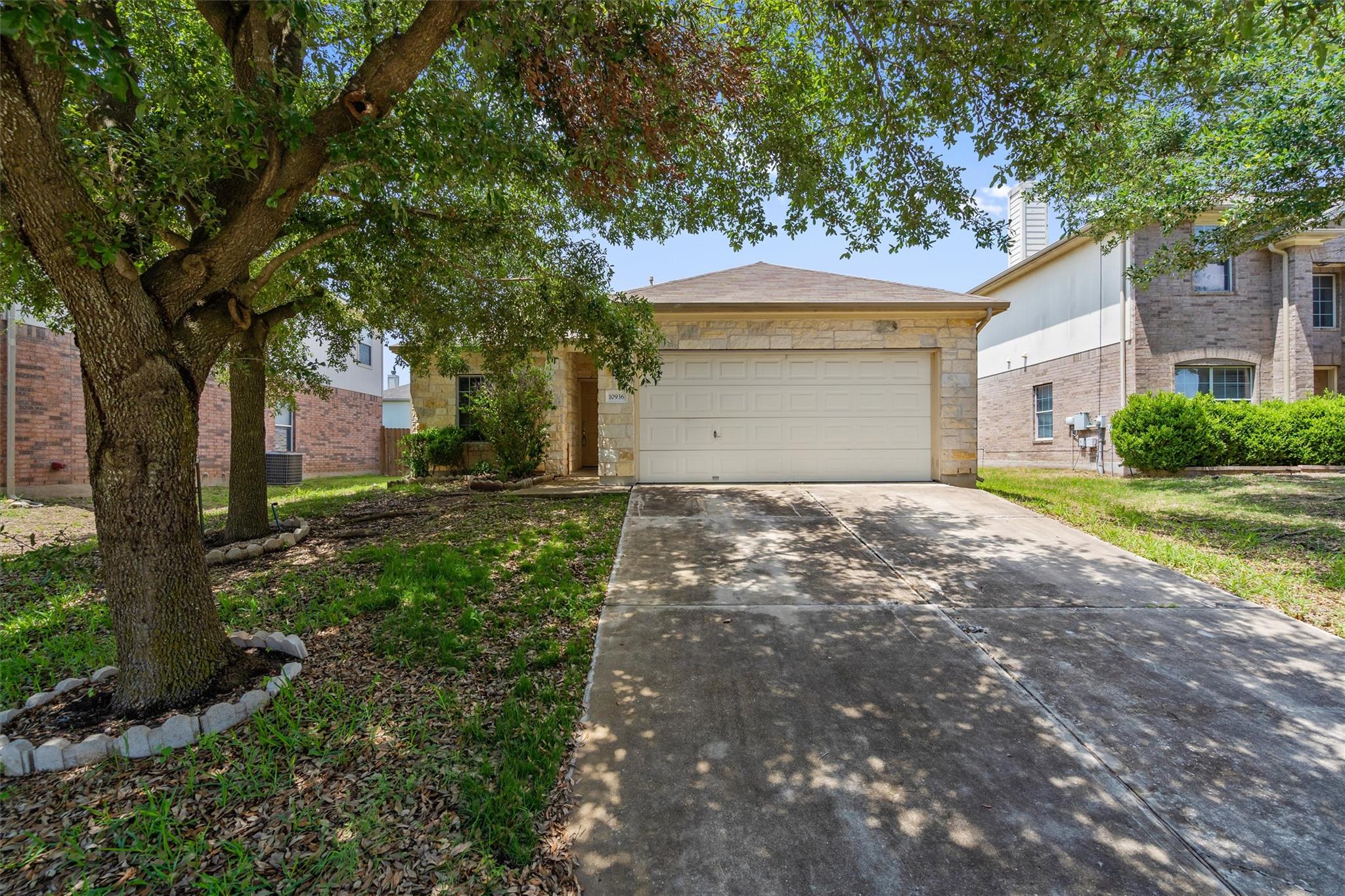Mature trees shade the concrete driveway leading 